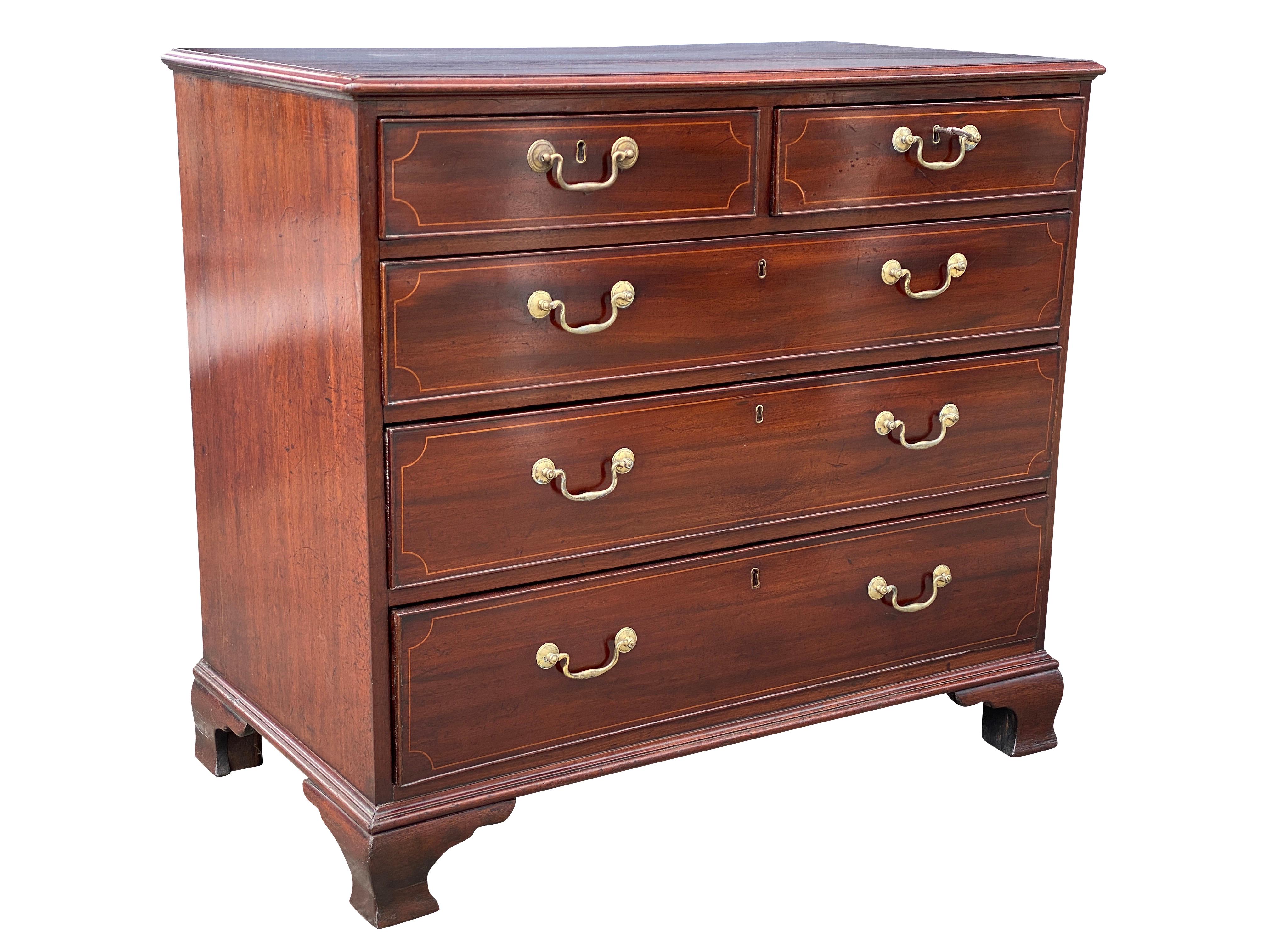 With a rectangular molded top over a pair of drawers over three long drawers all with brass bail handles and string inlay, raised on ogee bracket feet. Photographed outdoors so it appears redder in color than actual.