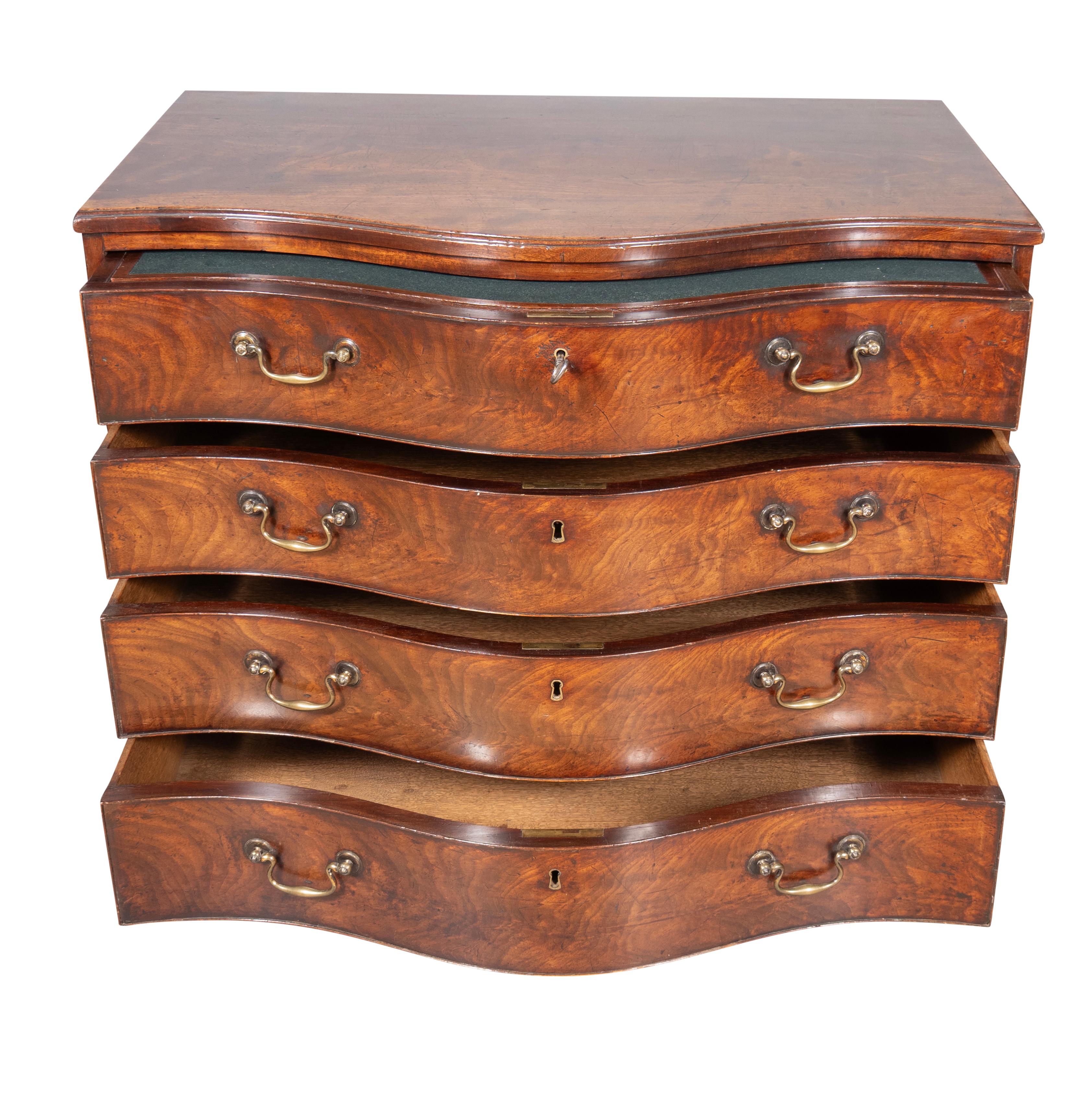 With serpentine top with four conforming drawers. The top drawer with a sliding panel writing surface with a fitted interior over three other conforming drawers. Bracket feet. Drawers with bail handles. Side handles. Finest quality piece. Original
