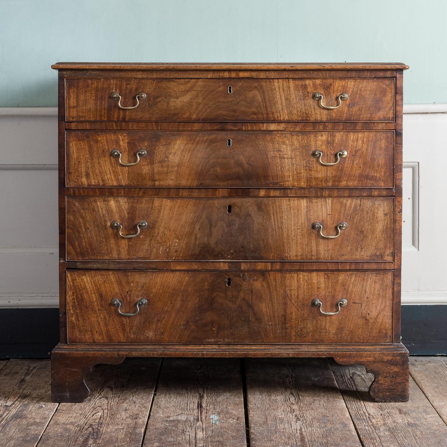 A George III mahogancy chest of drawers, with four graduated drawers retaining original brass furniture, keys not extant, on shaped bracket feet.

The piece is structurally sound and all drawers run well. There is a small section of cockbeading