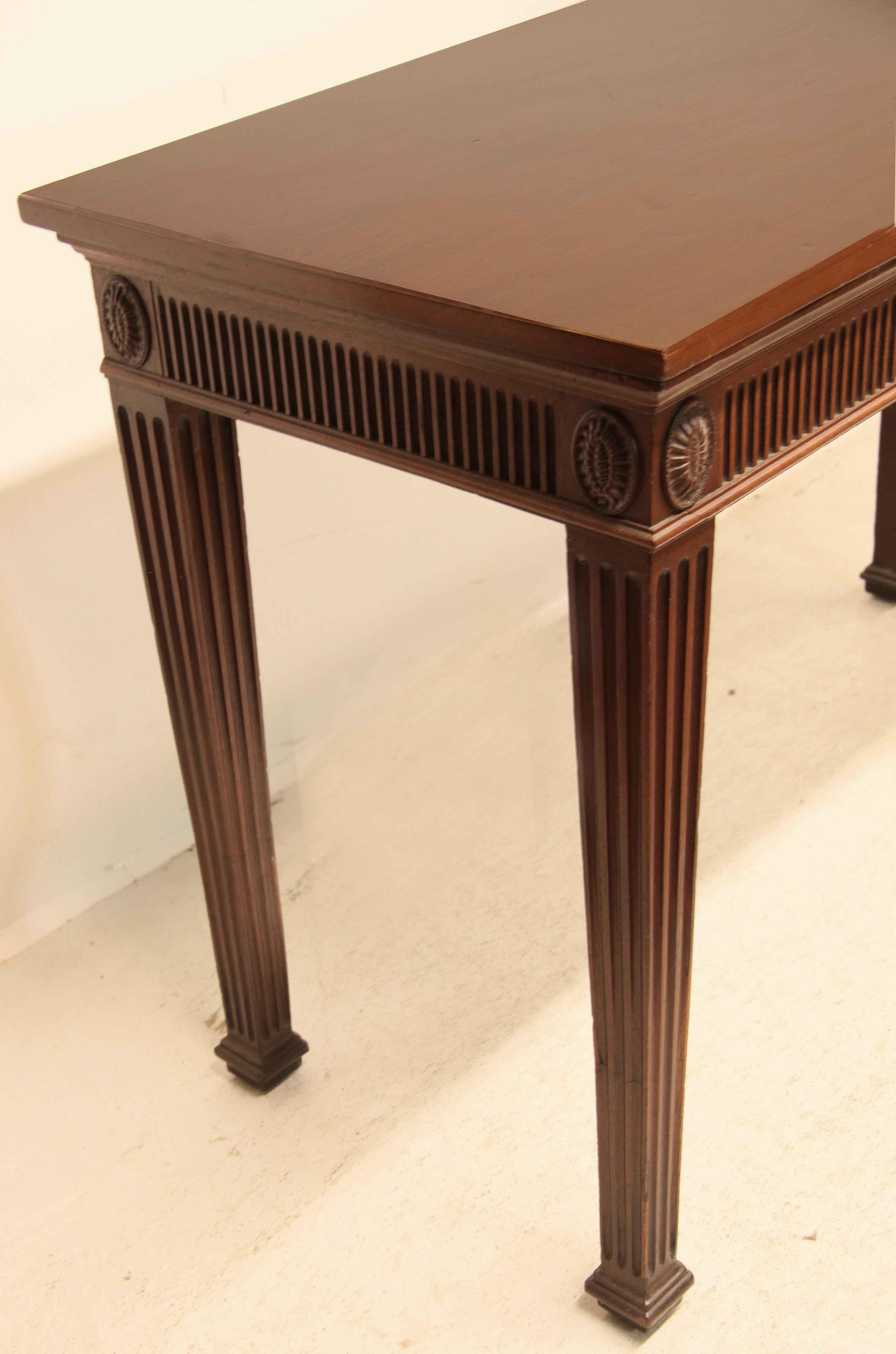 George III mahogany console table with understated elegance,  the top has nice figuring and color,  the frieze is reeded around the front and sides with vertical oval medallions at the corners;  reeded and tapered legs terminate with cove molded