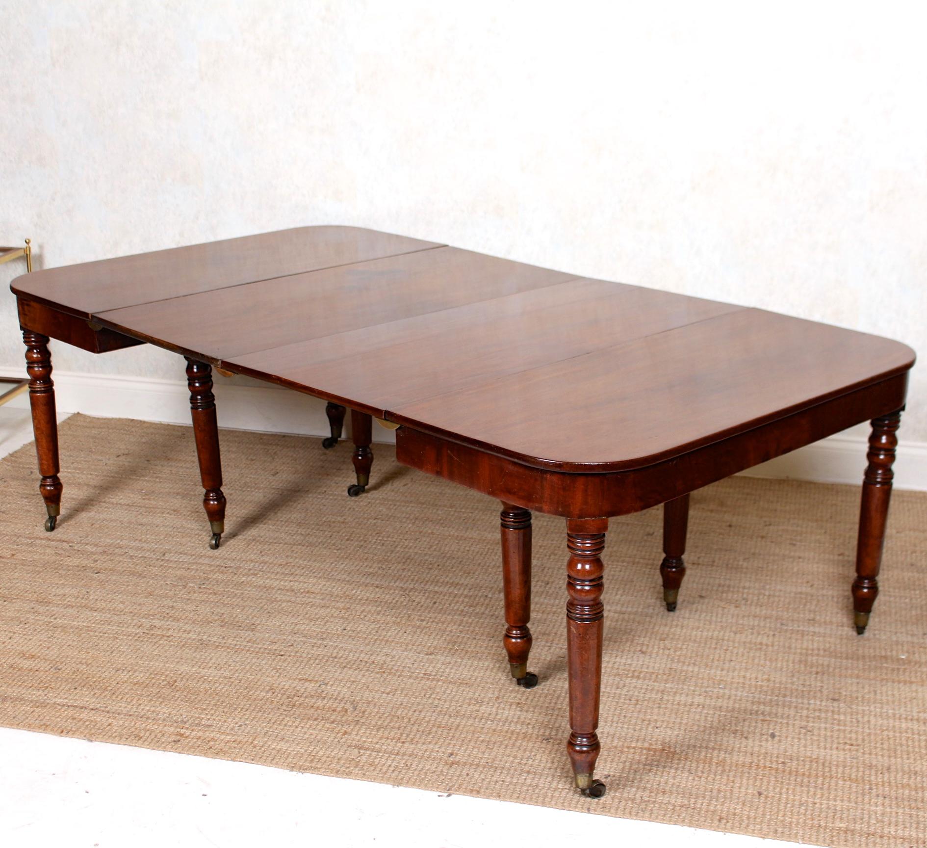 An impressive George III period mahogany dining table.

The top and apron - extending by way of spare leafs - with rounded corners and raised on turned tapering legs terminating in brass capped castors.