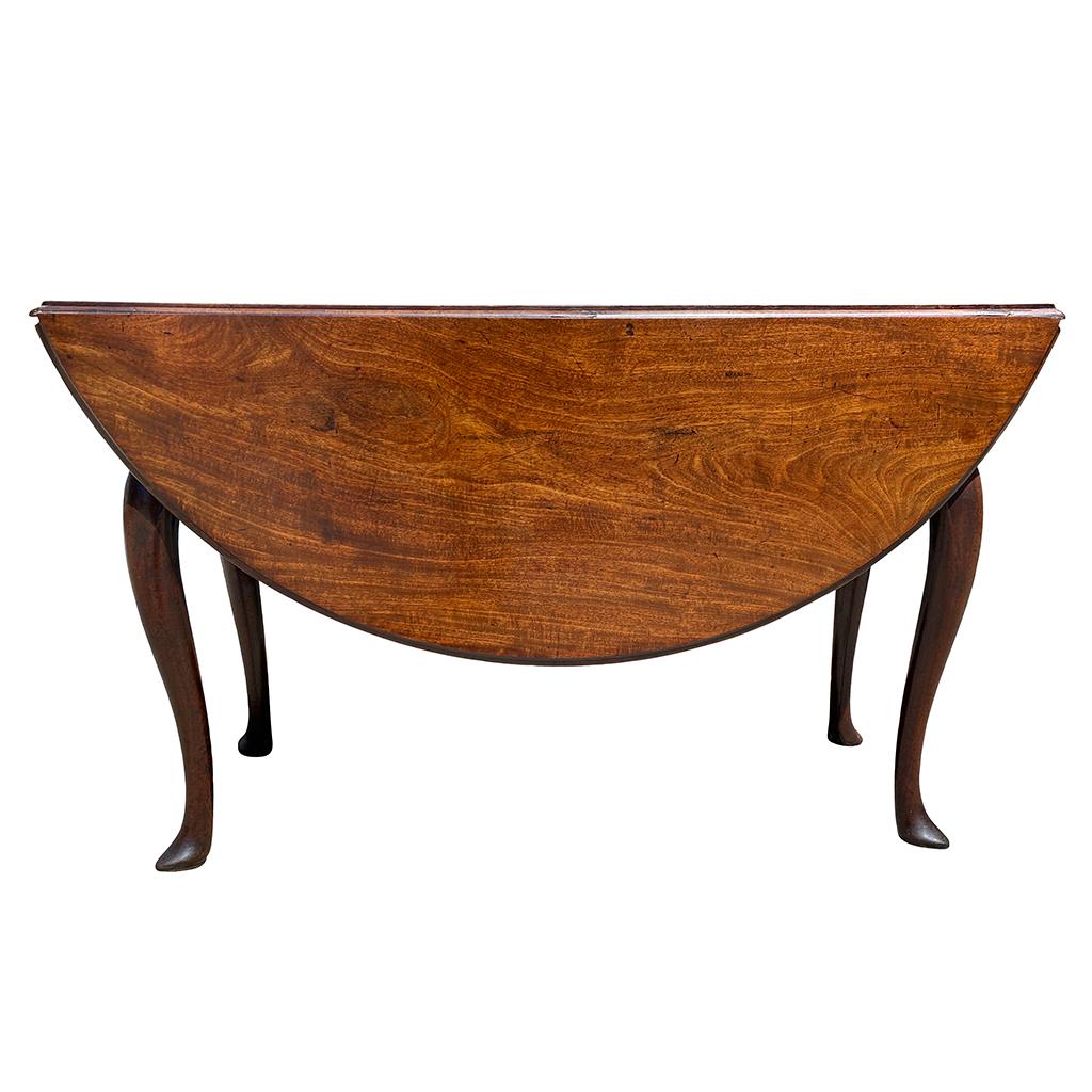 Beautifully figured mahogany top with drop leaves that open to create a circle. Containing a frieze drawer. Raised on cabriole legs ending on pointed pad feet.