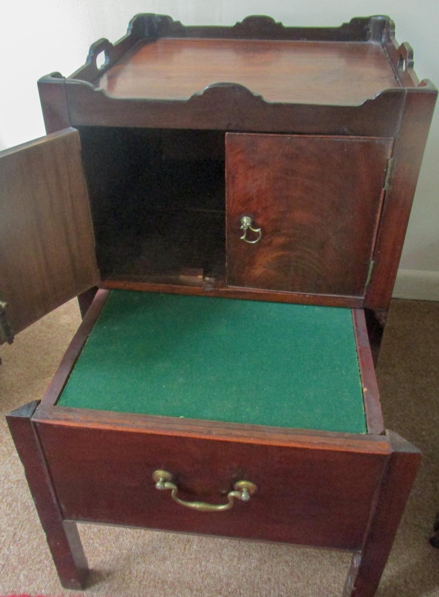 Georgian period mahogany English bedside table commode featuring a full scalloped gallery top with pierced handles and two-paneled cupboard doors above a single deep pull out surface covered with felt. This surface started out as a single drawer but