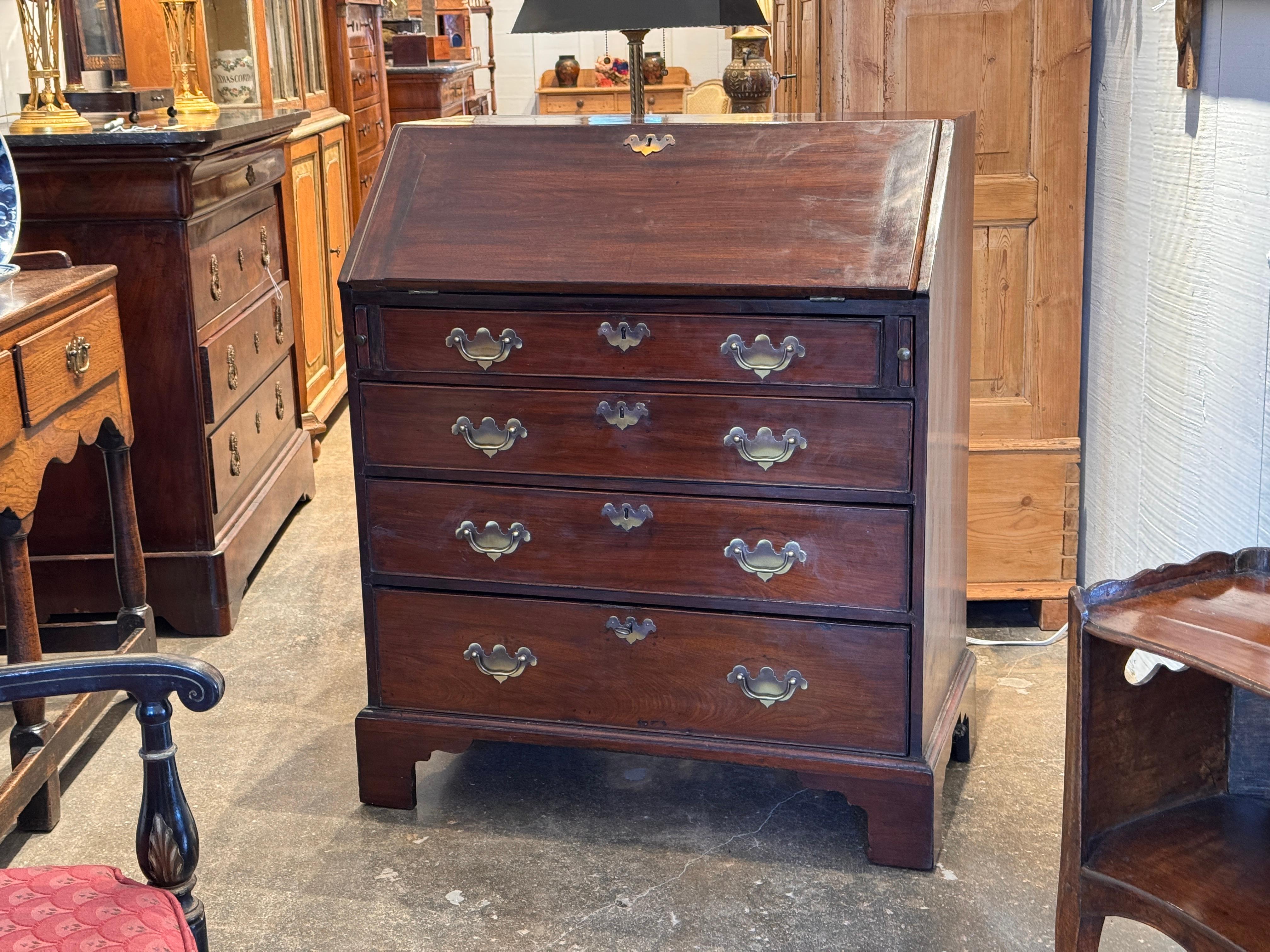 Scrivania in mogano di George III con un interno attrezzato con piccoli cassetti, scomparti aperti e un armadietto centrale fiancheggiato da colonne tornite. Le viste ravvicinate mostrano la semplice struttura dei cassetti interni e la disposizione