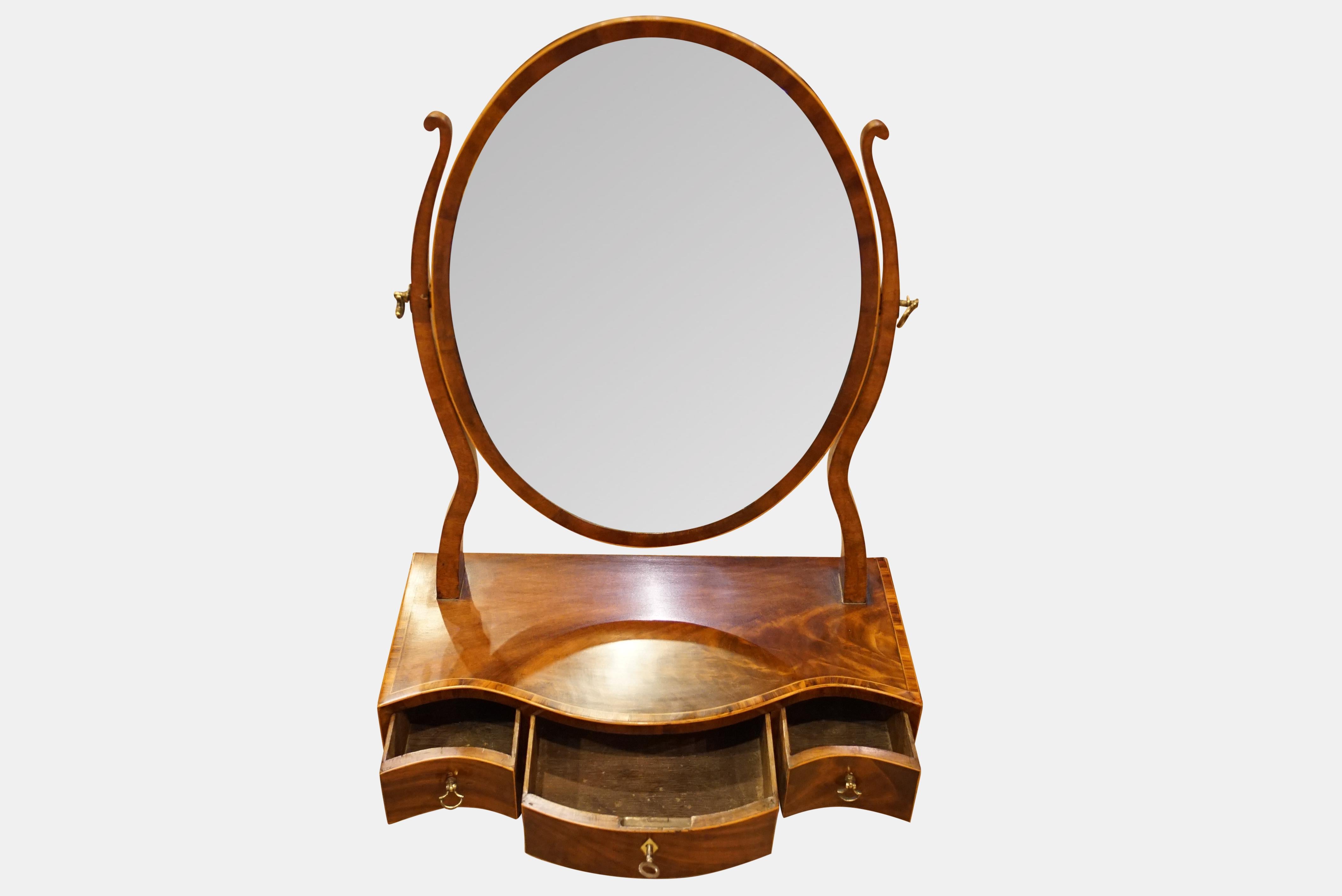 A George III mahogany framed dressing mirror, the base with serpentine front and three drawers crossbanded in rosewood,

circa 1800.