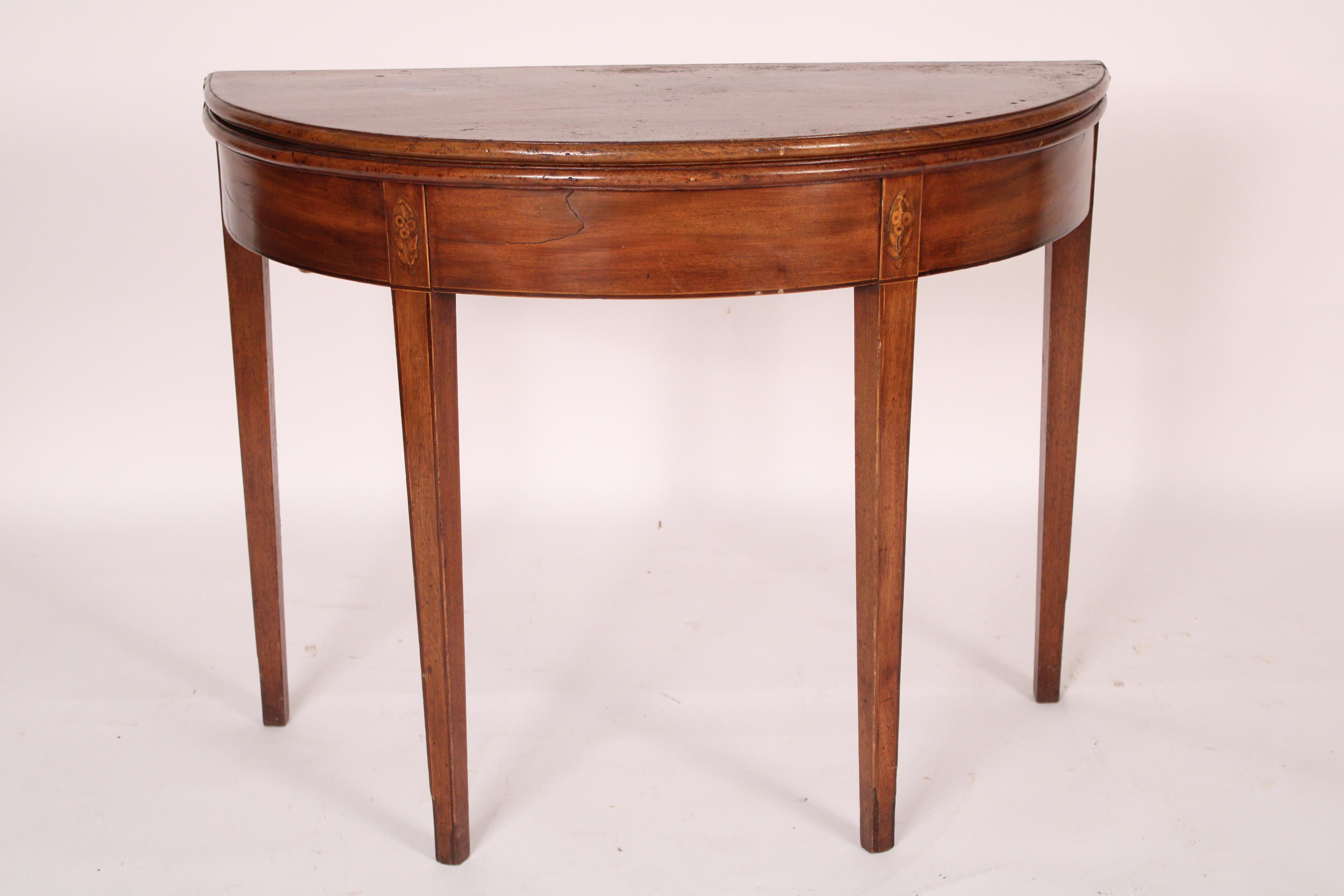 George III mahogany demi lune games table, circa 1800. With a demi lune top with molded edges, demi lune shaped mahogany frieze, front legs with patera inlay at top of legs, legs are square and tapered with line inlay. The two halves of the demi