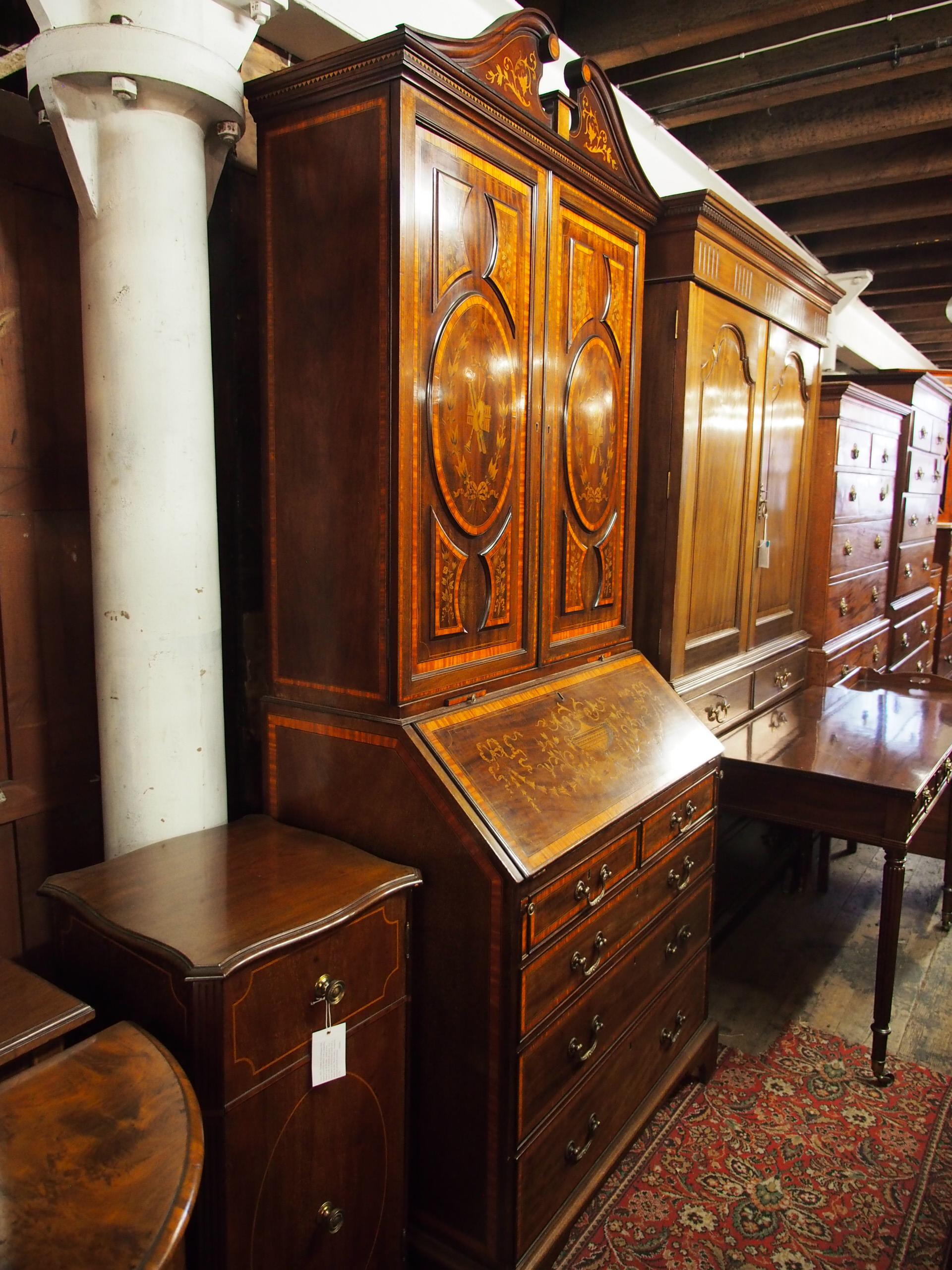 George III and later mahogany inlaid bureau bookcase, circa 1820. The top has an architectural pediment with foliate panels left and right and a diamond satinwood and ebony inlaid cornice. Below this are two doors with raised marquetry panels, with