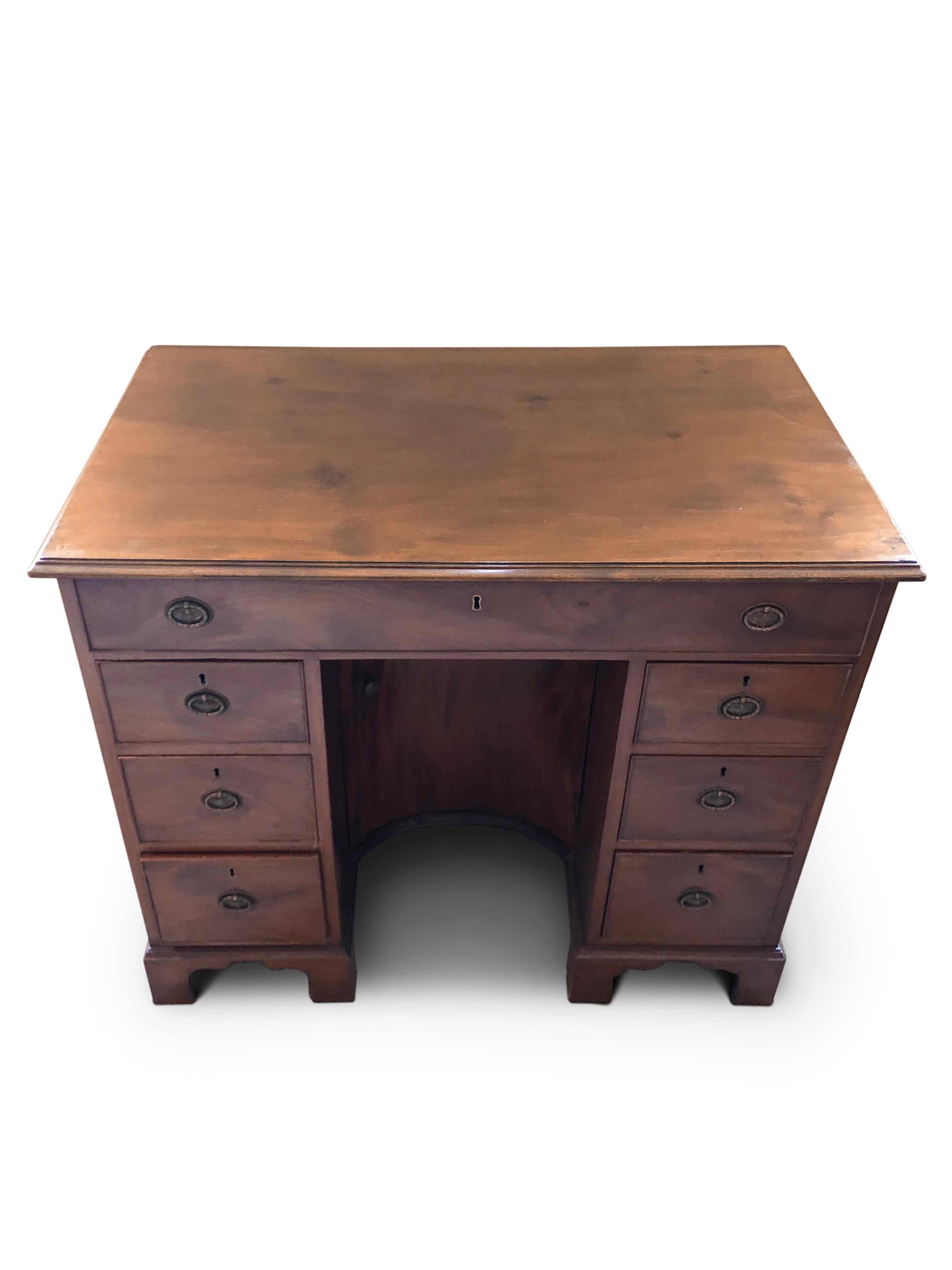 George III mahogany kneehole desk.
Thumbnail edged top, with large drawer beneath. Central 'Concave' shaped Cupboard flanked by three drawers either side. All resting on small bracket feet.