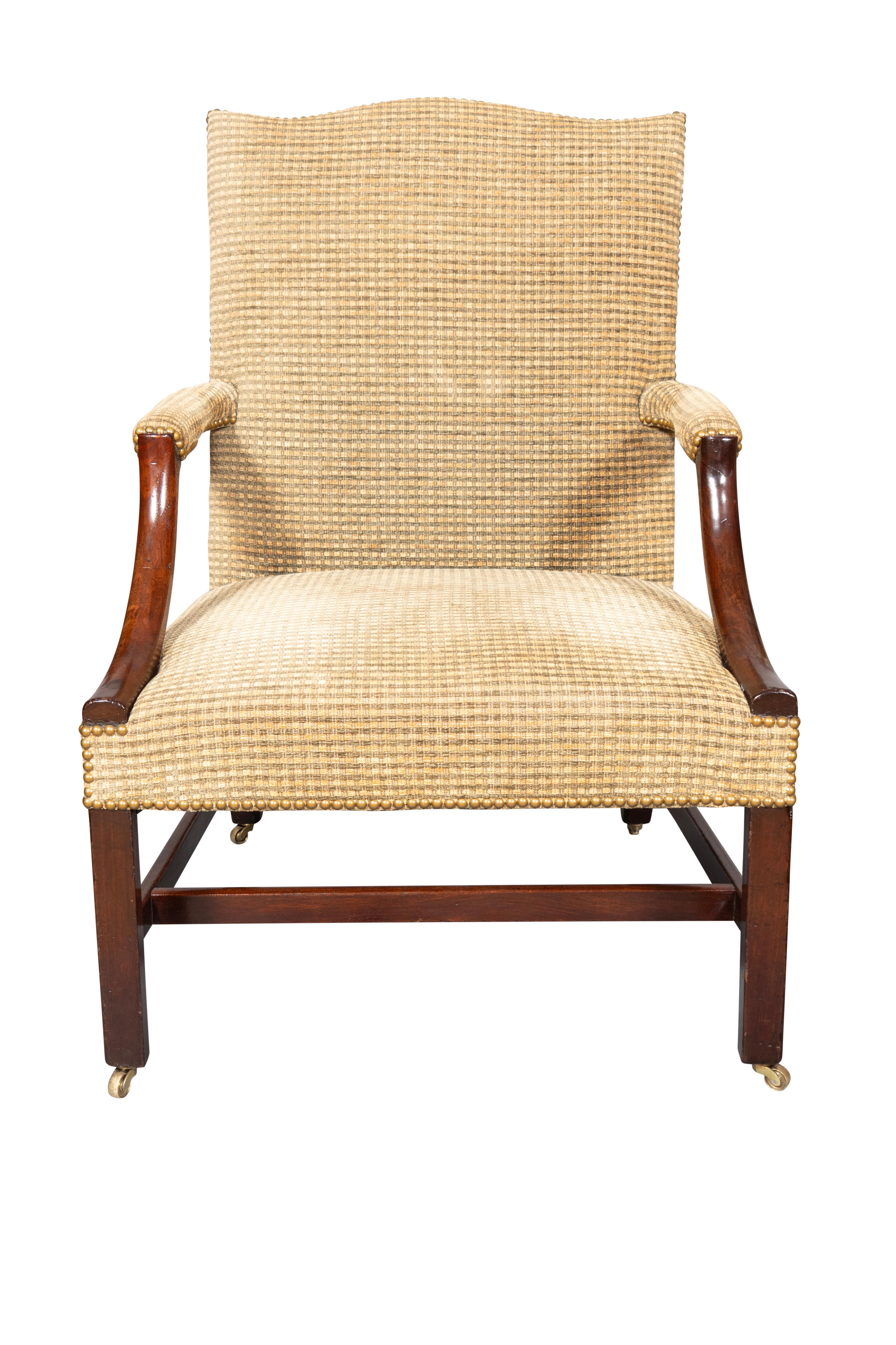 With serpentine upholstered back and square seat with typical down swept arms. Square section legs . H- stretcher and brass casters.