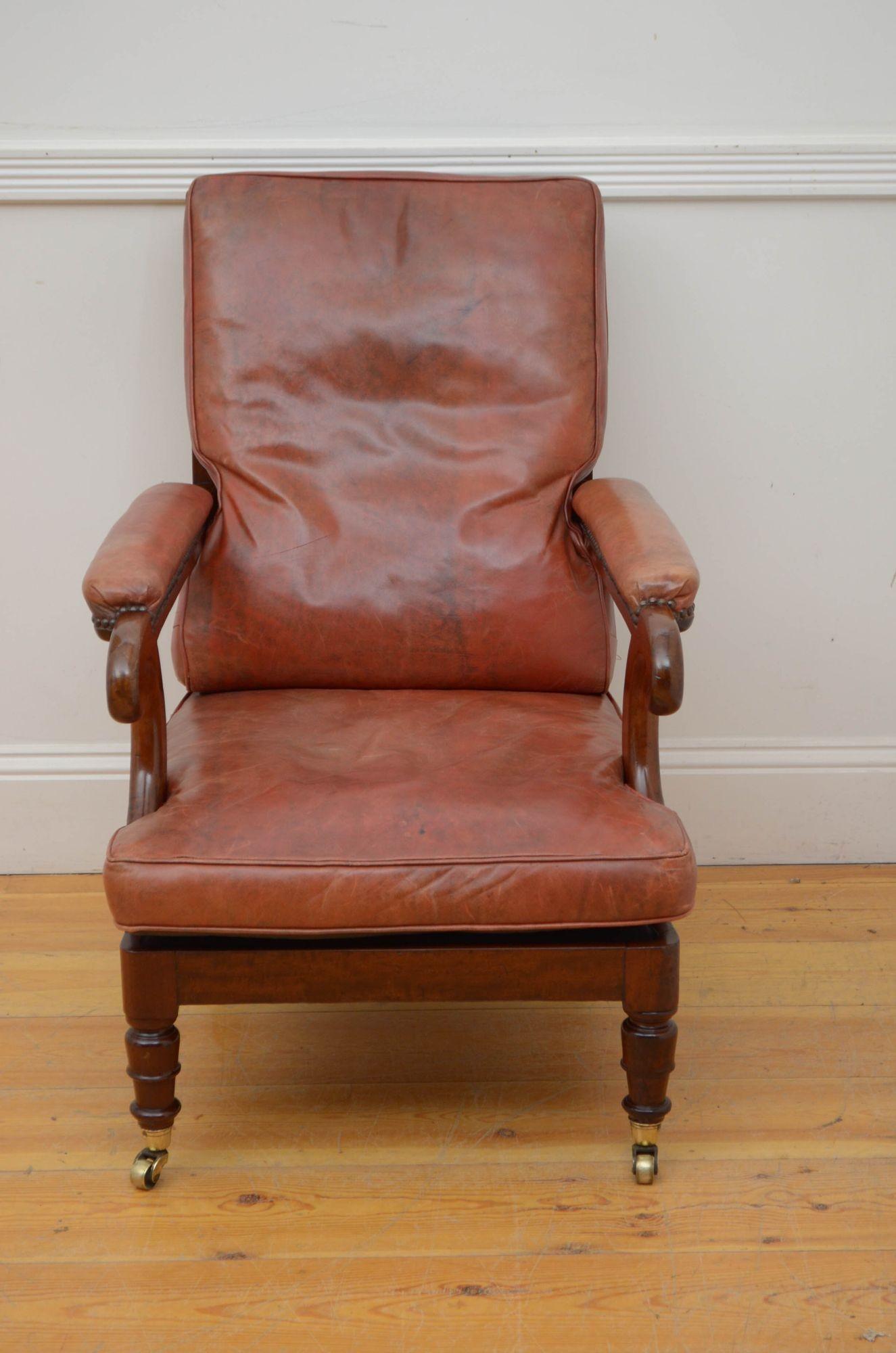 A05 Fine quality Georgian mahogany library chair, having caned back with marron leather cushion, generous seat and leather padded scroll arms, all standing on turned legs terminating in brass castors. This antique armchair came from a private