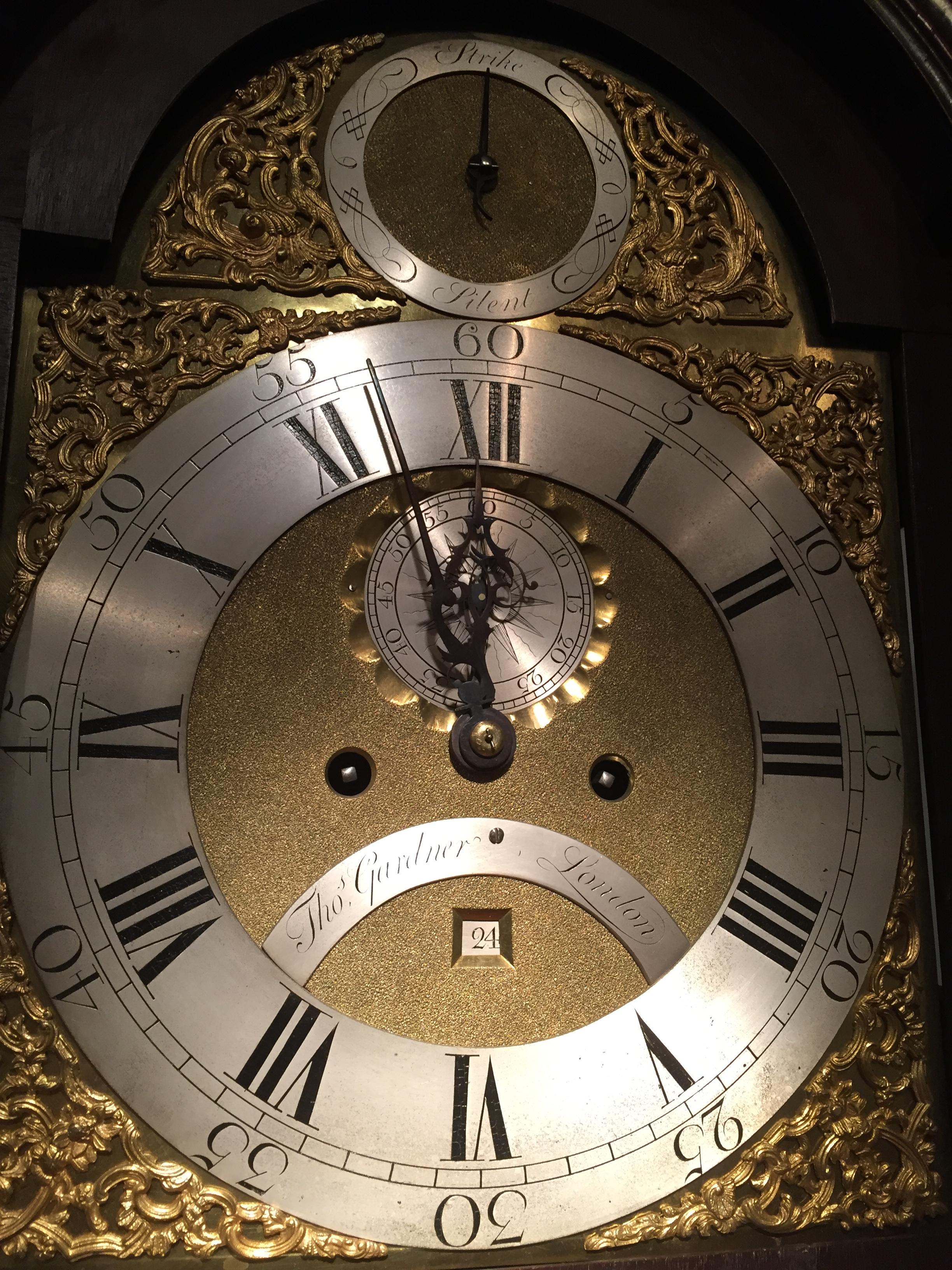 A fine antique George III period mahogany eight day longcase clock with figured mahogany case. The hood with brass capped corner columns, arched top with 3 brass spire finials, interspersed by a scalloped edge decoration.

The arched brass dial is