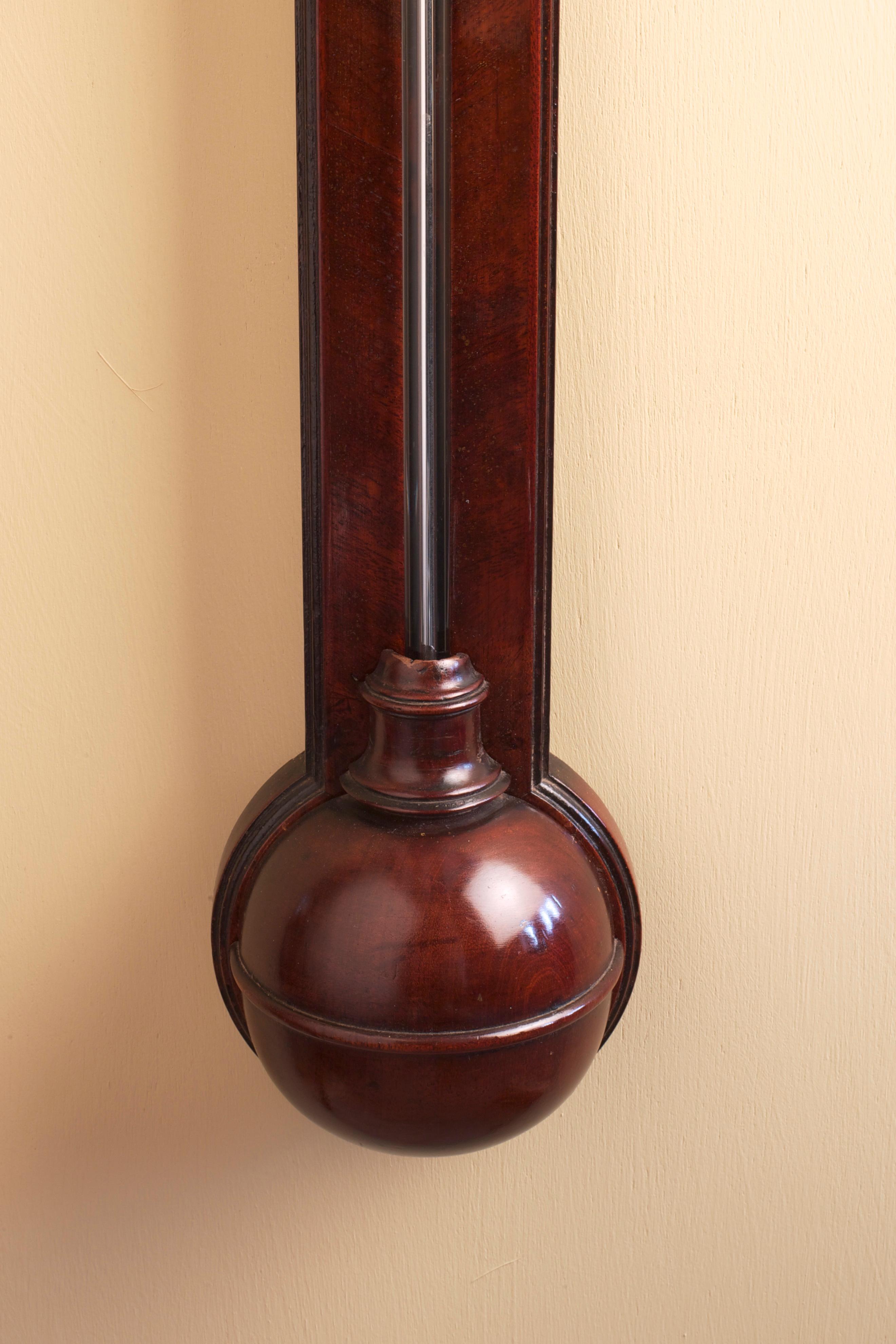 George III stick barometer in a finely figured mahogany case with canted corners and architectural pediment surmounted by a central ivory finial. Exposed mercury tube with bulb cistern and bulbous cistern cover. Beautifully engraved register plate