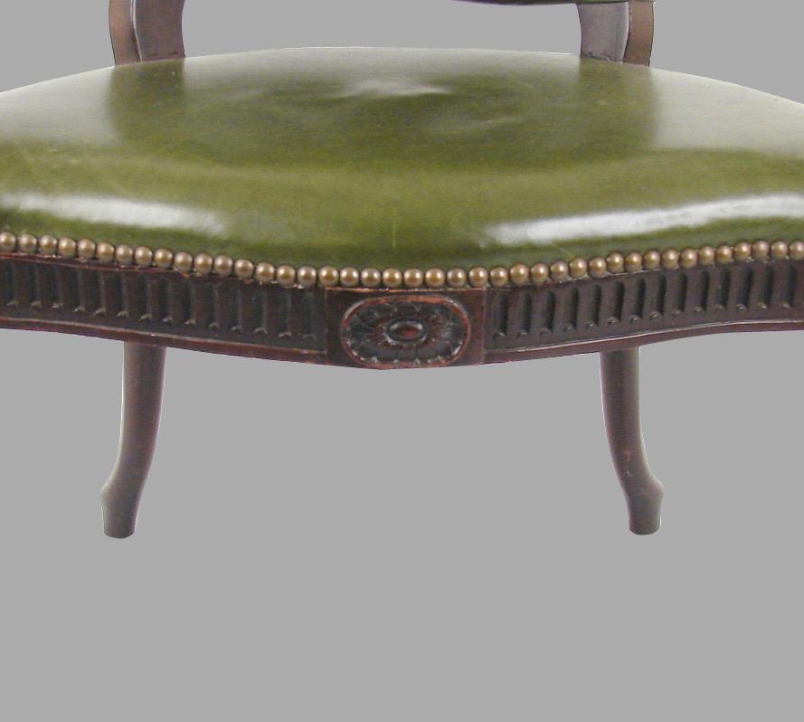 A George III mahogany leather upholstered open arm chair in the French Hepplewhite taste with nailhead trim, the serpentine front rail supported on reeded front legs with down swept rear legs, circa 1800.
