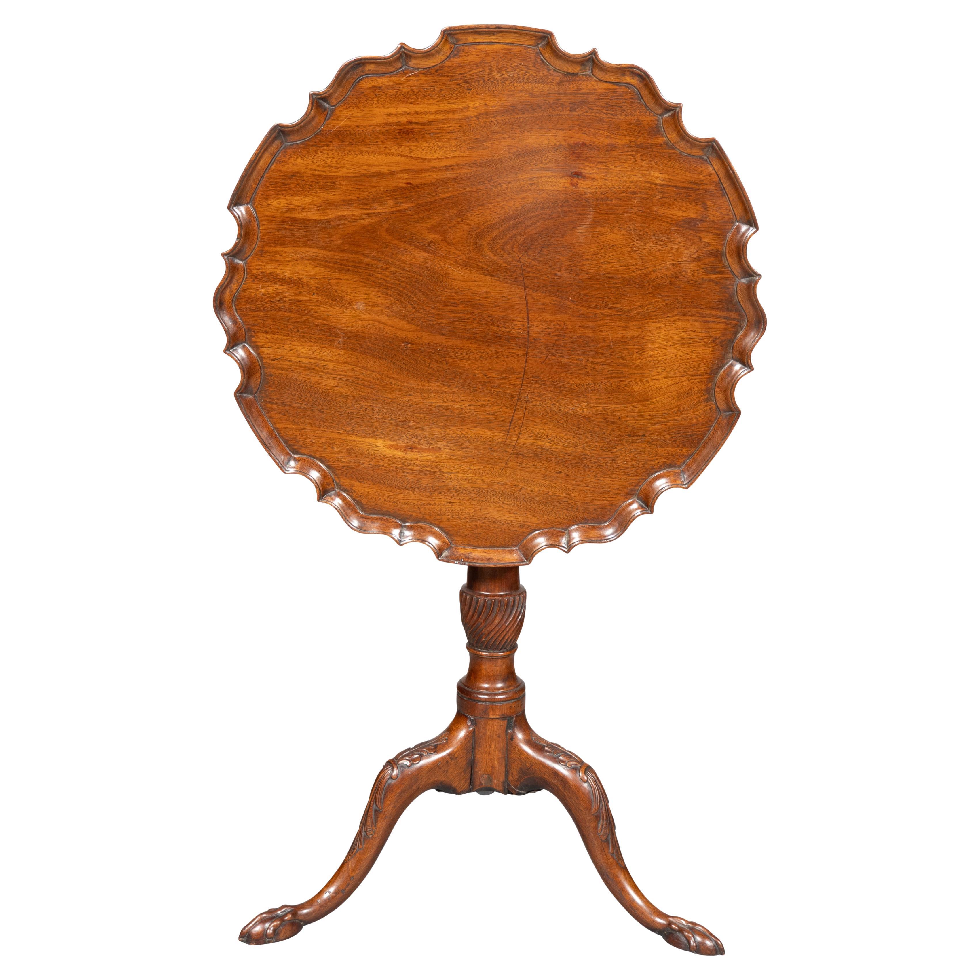 Circular hinged top with pie crust edge mounted on a turned support with fluted spiral urn and three cabriole legs with leaf carved knees ending with ball and claw feet.
