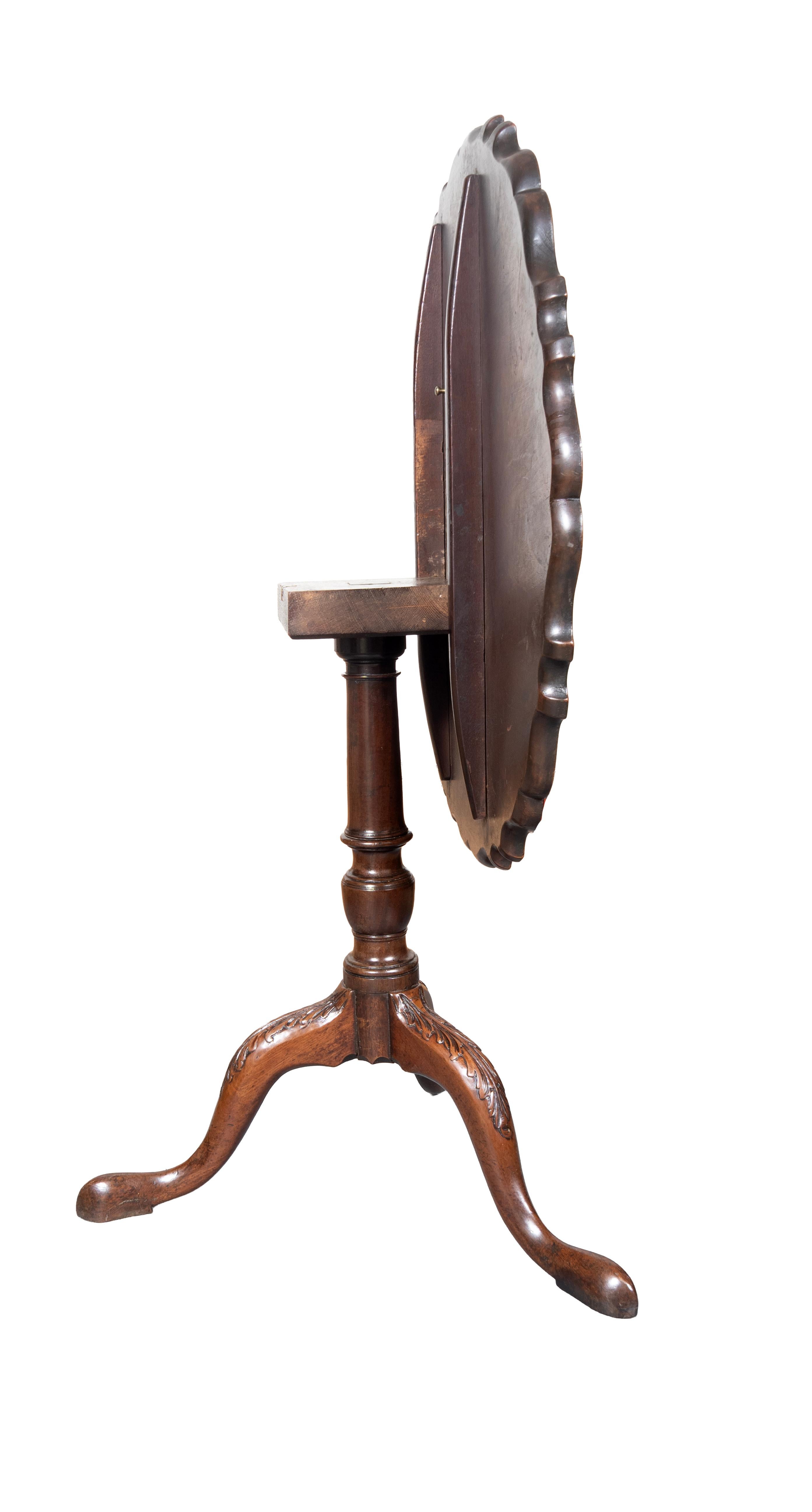 Hinged circular top with piecrust edge on a turned urn form support and ending on three cabriole legs with leaf carved knees.