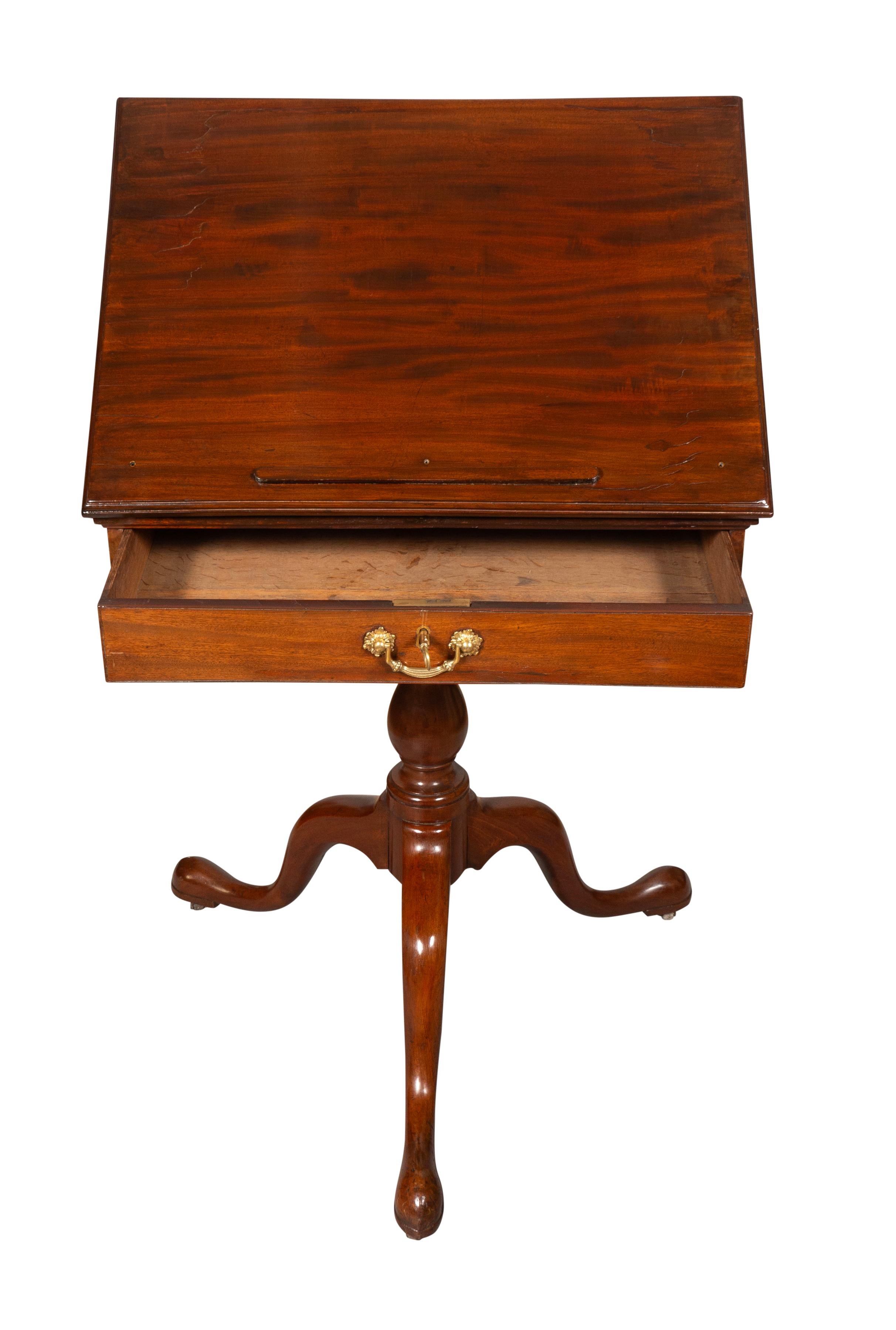 Rectangular hinged top over a drawer. With turned baluster support ending on three cabriole legs.