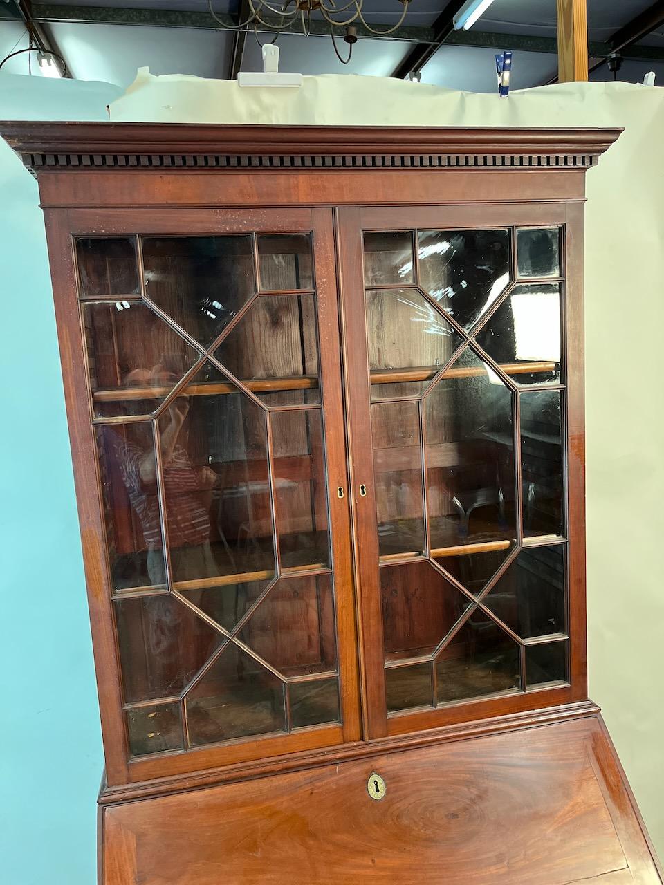 Secretario de caoba Jorge III con cristal original.  
Pátina sobresaliente con latones y pies de ménsula originales.
Dos piezas.  Caoba y pino.
