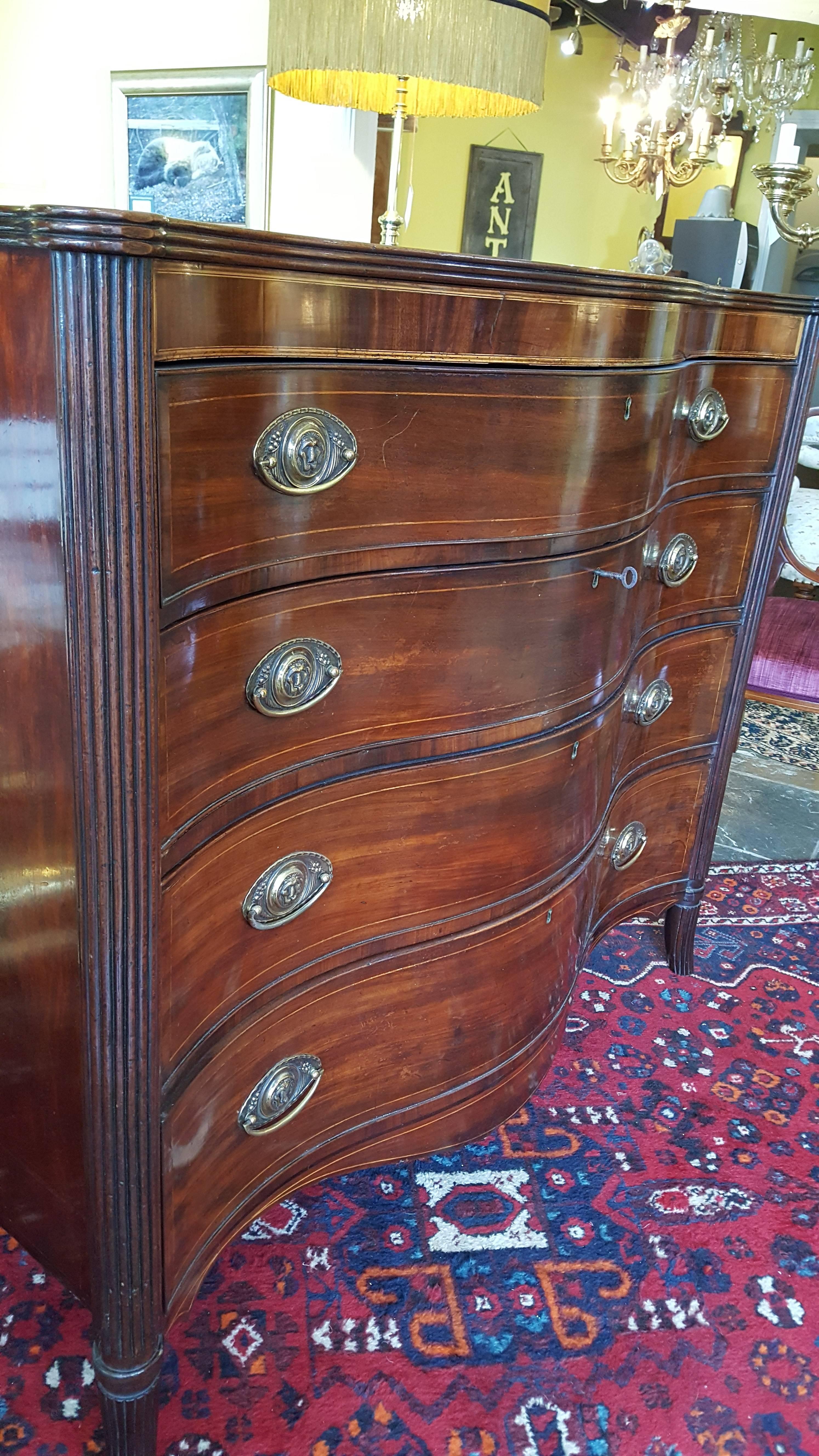 George III mahogany serpentine front and top chest of drawers with shaped apron and satinwood string inlay, lion mask handles, reeded columns leading to splayed feet, circa 1790. Measures: 48