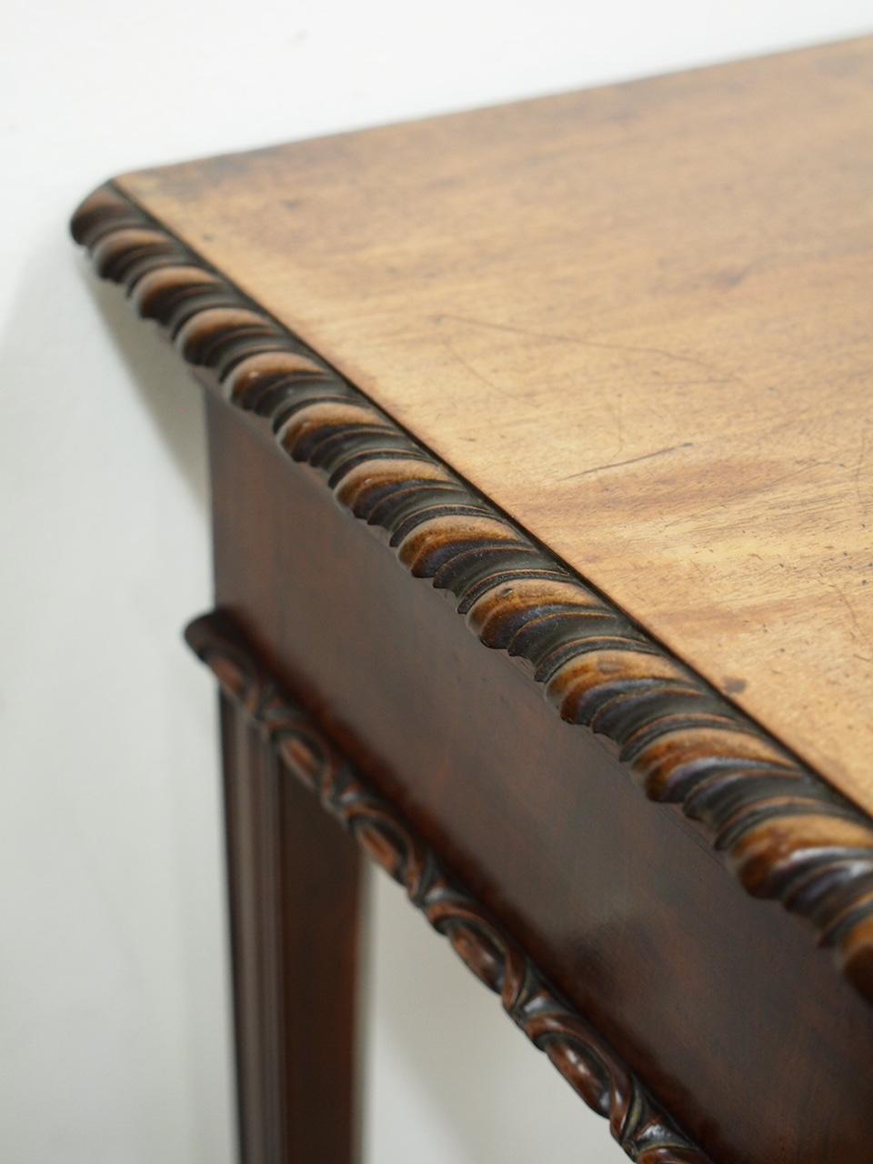 George III mahogany serving table. With figured mahogany top and a carved gadrooned fore-edge which is above a deep apron in flame mahogany and a carved foliate design. Standing on square legs, which have been chamfered to the inside, and are reeded
