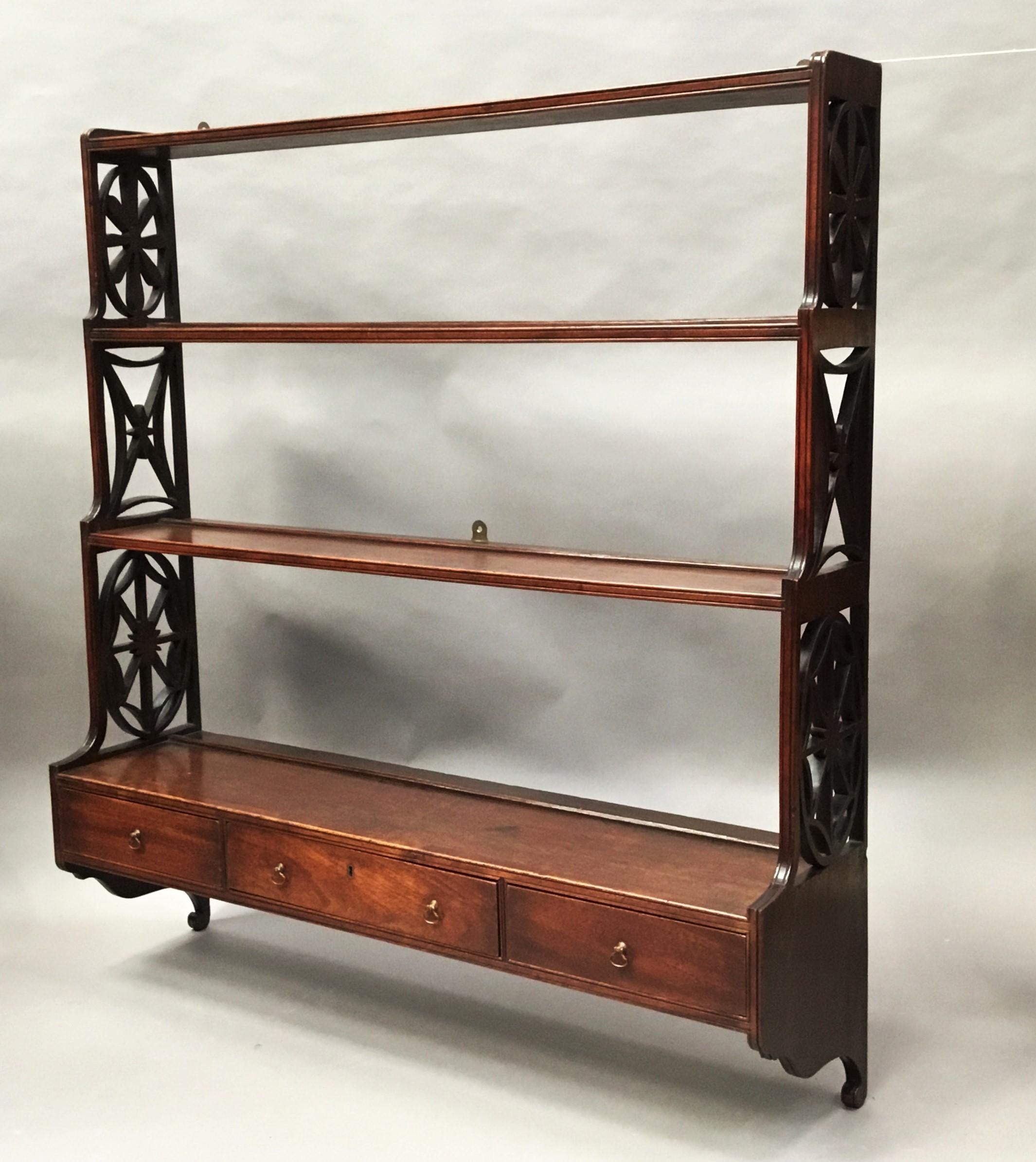 George III mahogany set of 'Chippendale' hanging wall shelves; of graduating form. The 4 graduating shelves supported on good carved open fret sides of 3 differing Chippendale inspired designs; and a scroll bracket below. The bottom shelf with 3