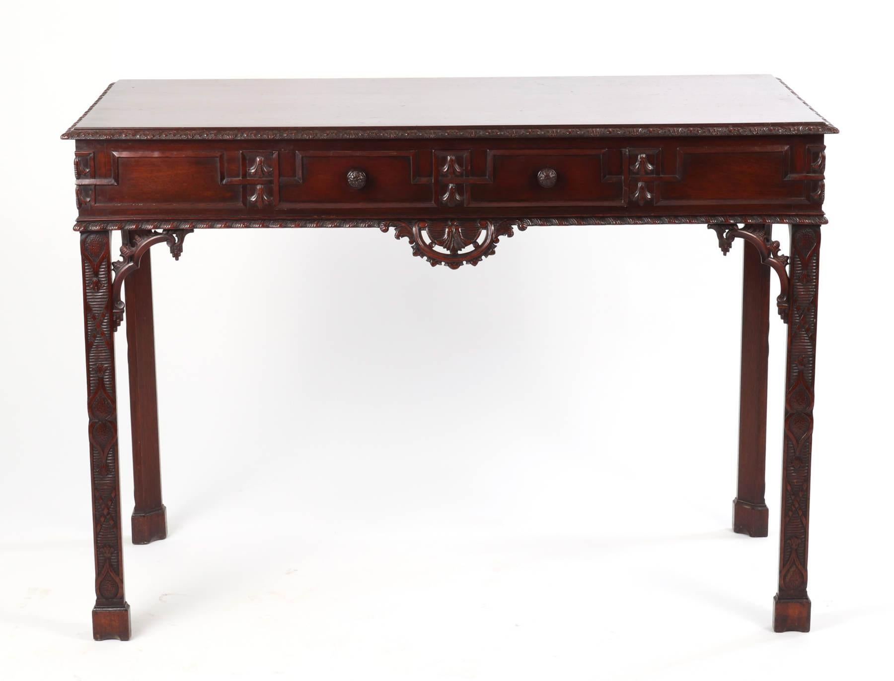 Fine George III mahogany side table, the rectangular top with carved edges over the frieze having a single drawer with carved wooden knobs, the applied fretwork and bellflowers over the gadrooned edge centered by a through carved cartouche, raised
