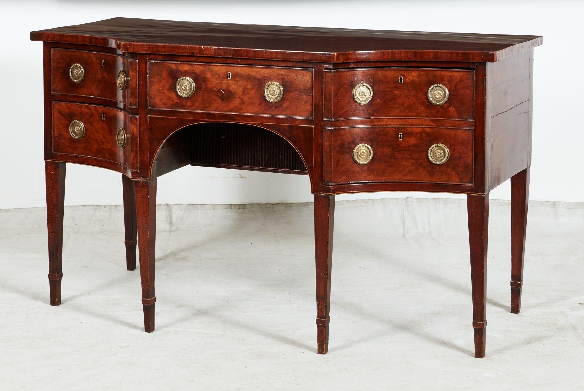 Raffinata credenza in mogano di George III con fronte sagomato, il piano in mogano con venature vivaci e riccamente patinato, sopra tre banchi di cassetti, il cassetto centrale sopra il foro per le ginocchia ad arco, il lato sinistro con due