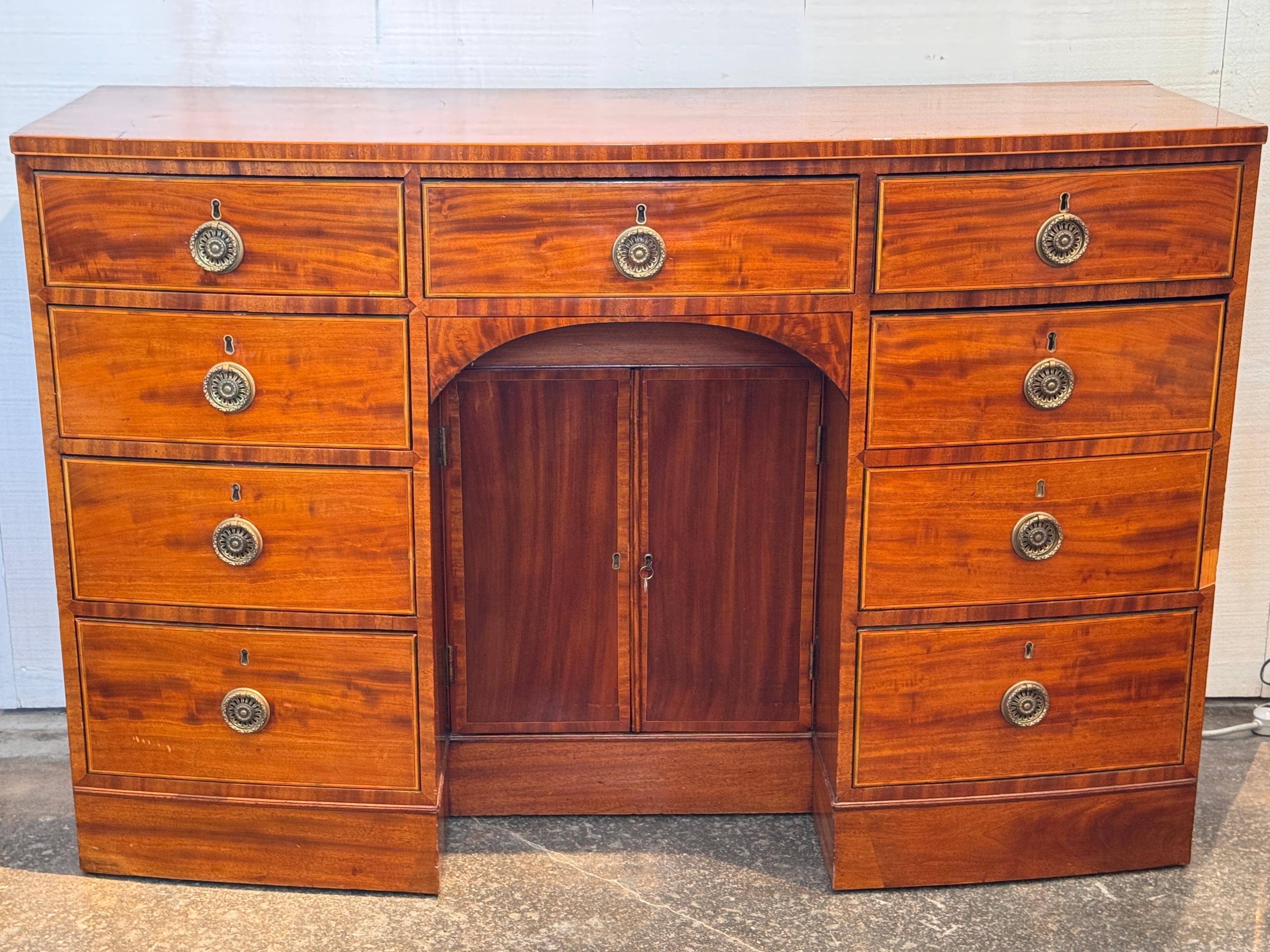 George III mahogany sideboard with a rich, warm patina and clean lines typical of the late 18th century. The case features an arched center cupboard flanked by banks of graduated drawers, all retaining original brass rosette pulls. Dovetail joinery