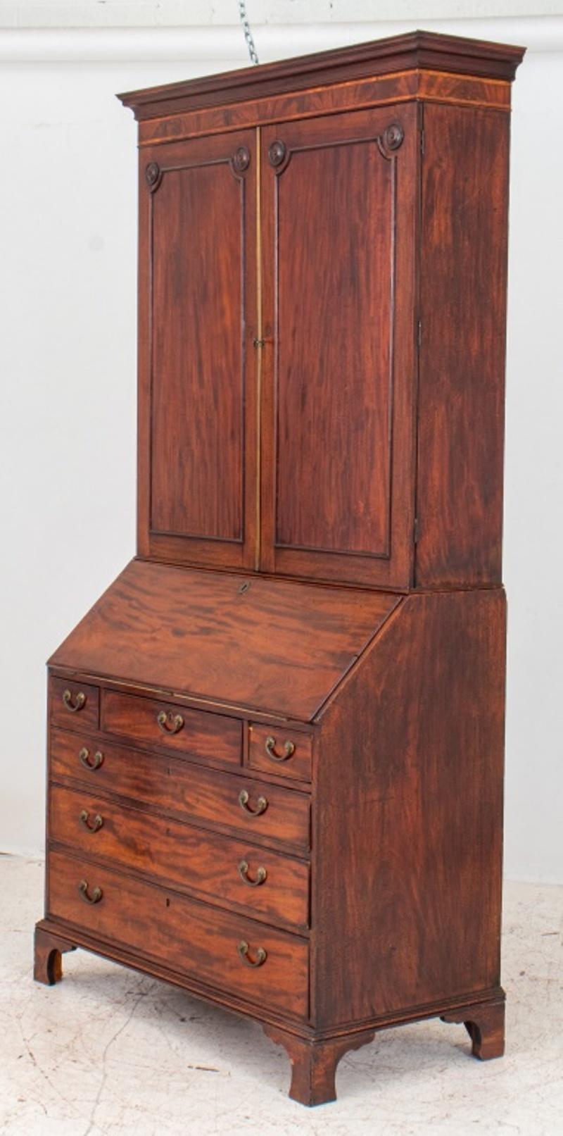 George III mahogany slant front desk with bookcase, circa 1800, the upper section with flat molded edge cornice and two paneled doors; the lower section with slant top opening to ten small drawers, eight cubby holes, and a small cabinet, the writing