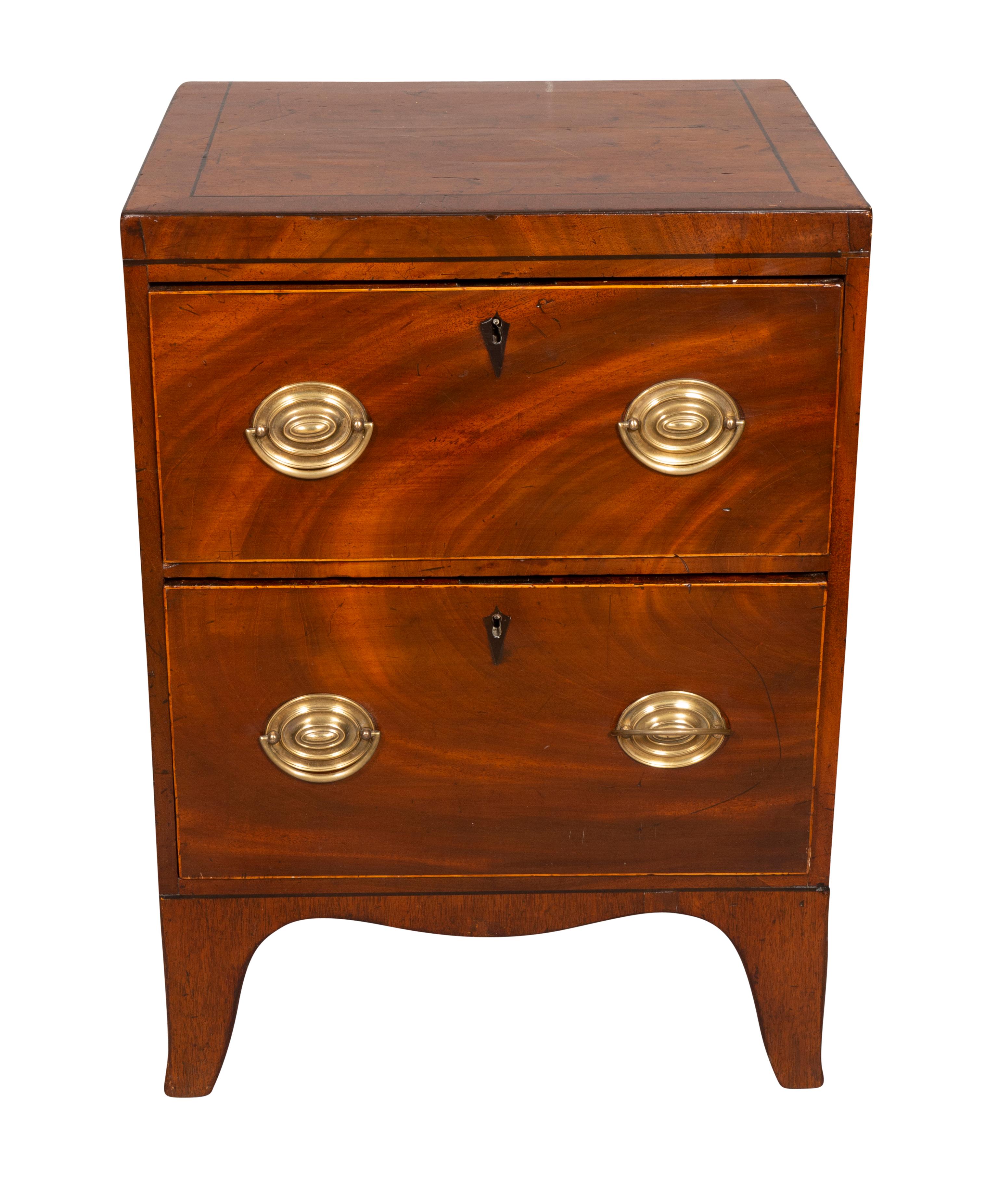 A cute chest of unusually small size perfect for a bedside table or end table. Rectangular top over two drawers. Oval brass handles and ending on French feet.