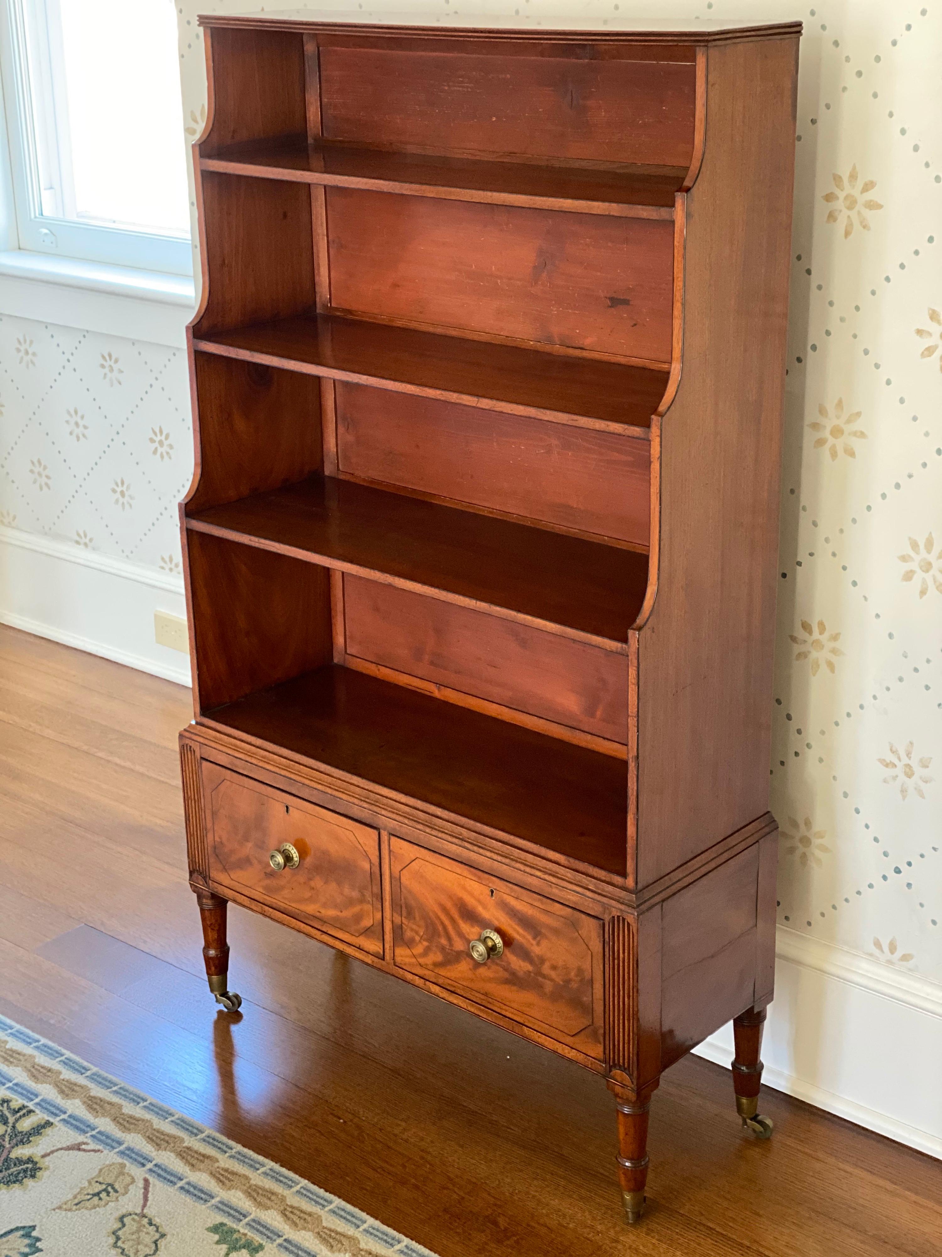 George III mahogany standing bookcase, circa 1800
The rectangular top above four stepped shelves, the frieze fitted with a pair of short drawers raised on turned tapering legs on casters.
Measures: 51
