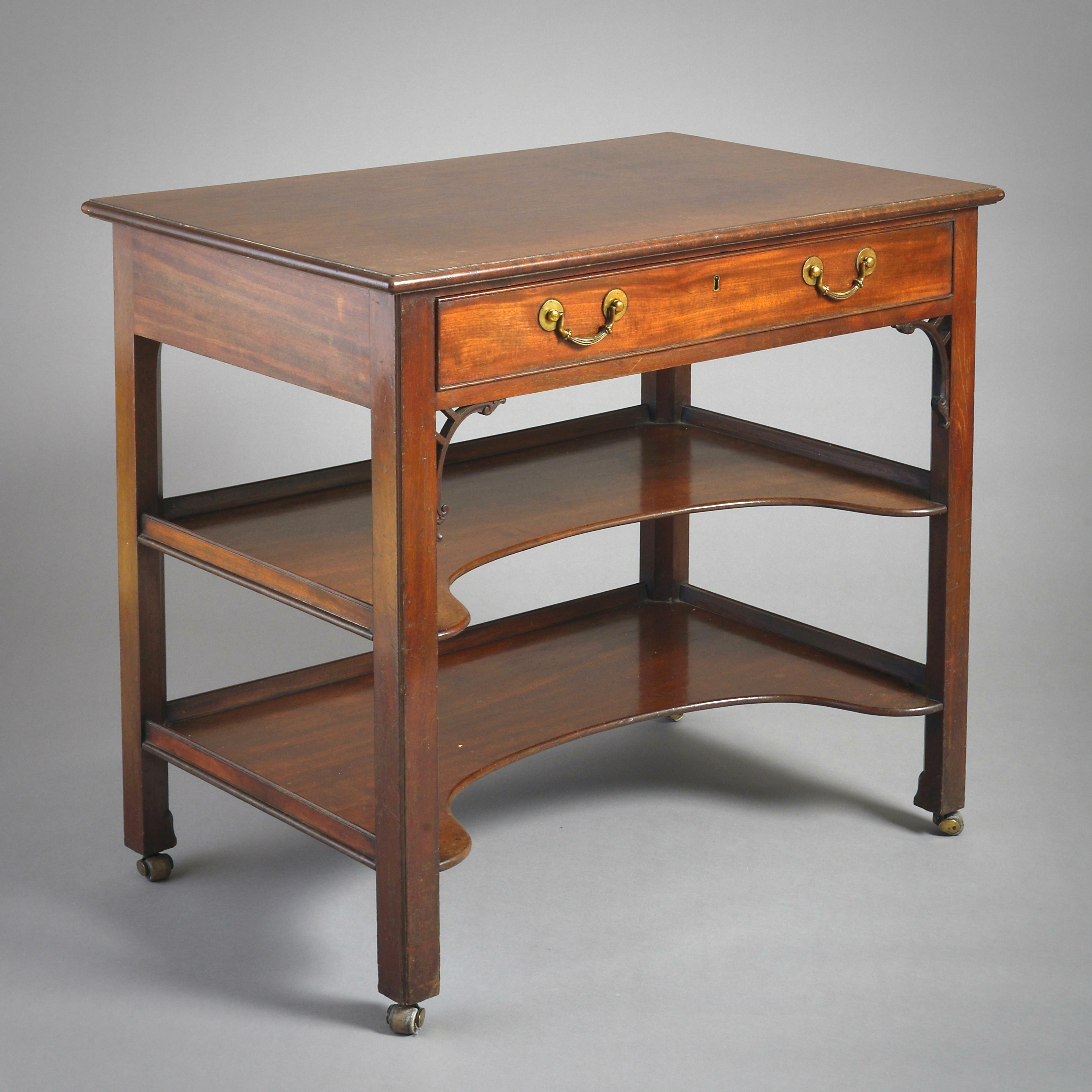 Table d'appoint à trois niveaux en acajou de style George III, vers 1760.

Avec un plateau finement figuré au-dessus d'un tiroir en frise, des consoles à volutes, et deux sous-plats galbés concaves sur des pieds carrés chanfreinés. Poignées