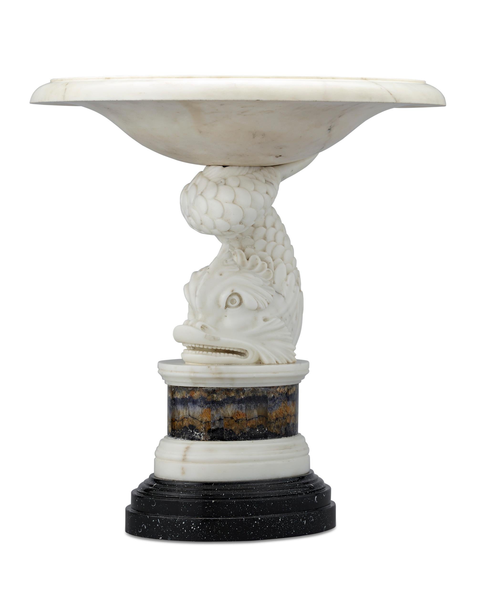 This important George III tazza is attributed to famed Scottish-Swedish architect Sir William Chambers. The magnificent piece features a base carved from statuary marble in the shape of a stylized dolphin, which relates to Chambers extraordinary