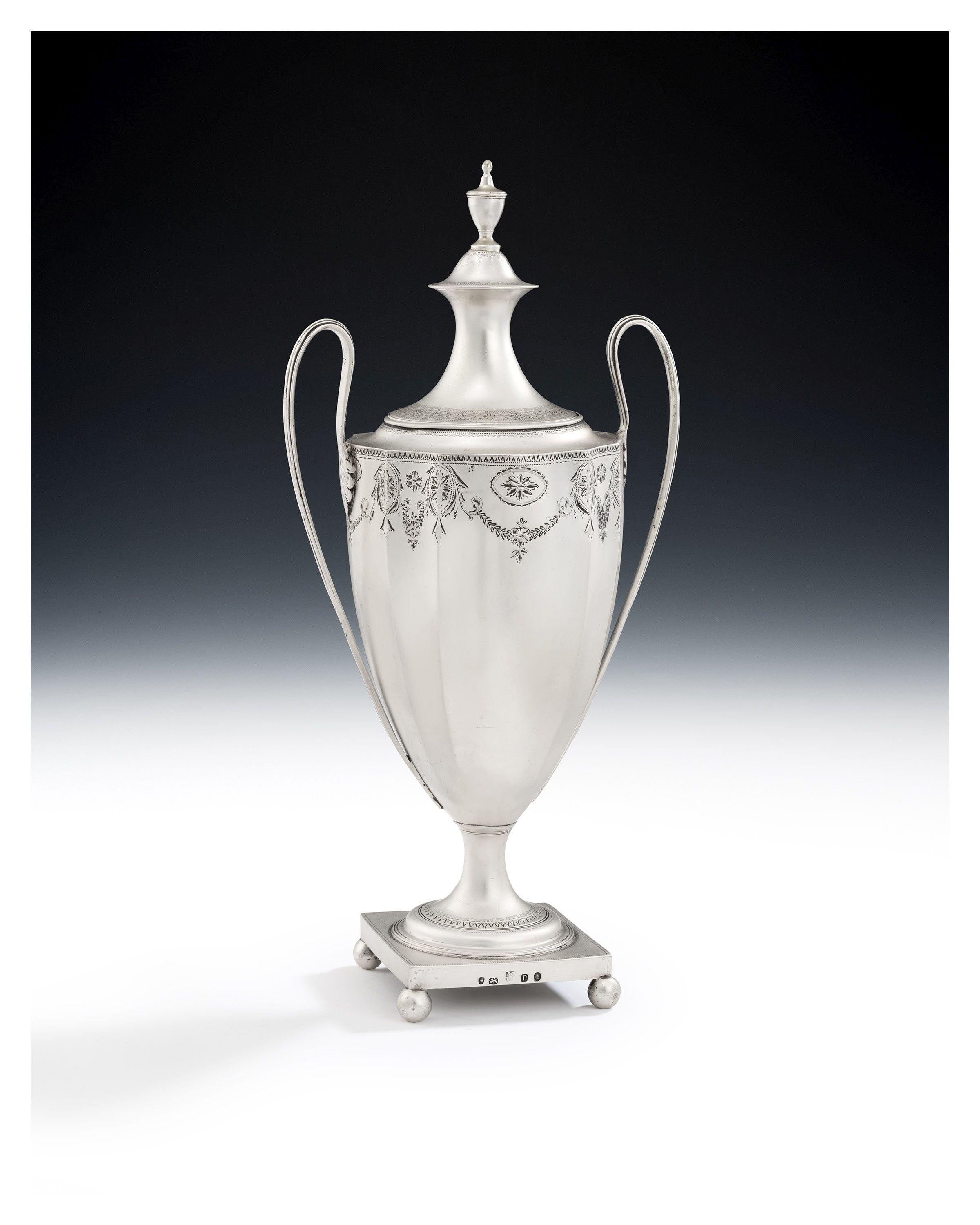 A very fine George III Neo Classical Water or Tea Urn made in London in 1790 by Samuel Godbehere & Edward Wigan.

This very fine piece stands on a square pedestal platform with four ball feet. The foot is decorated with reeding and bright cut and