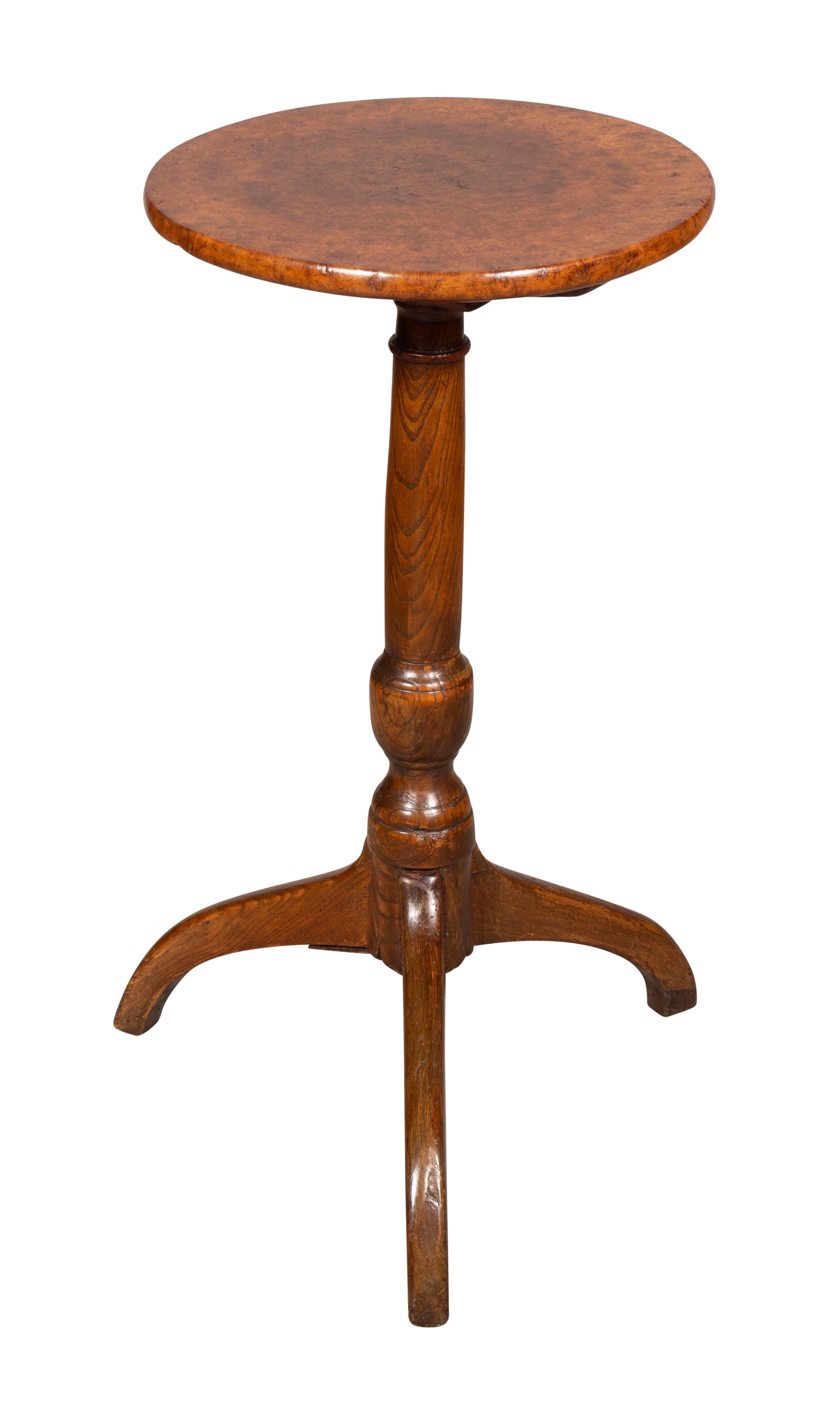 With a circular top with fine tight walnut burl over a turned post joined by a tripartite base.