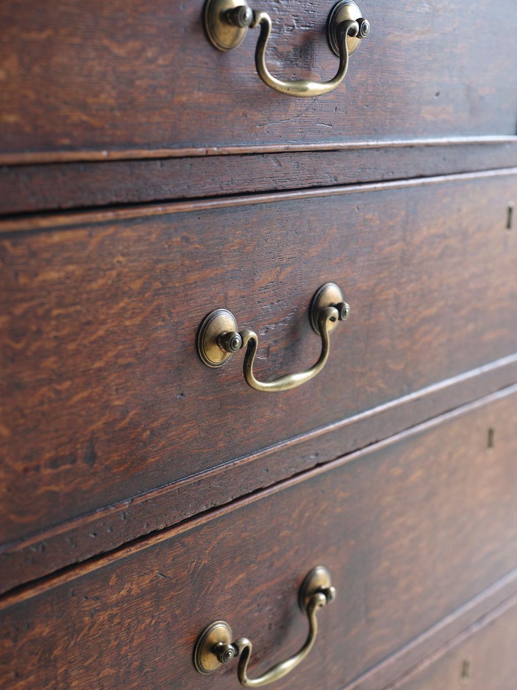 This is an elegant George III period oak chest of drawers. The medium dark patina has a beautiful patina. There are two smaller top drawers and 5 larger drawers. All of the drawers have key holes but this piece did not come with a key. The brass