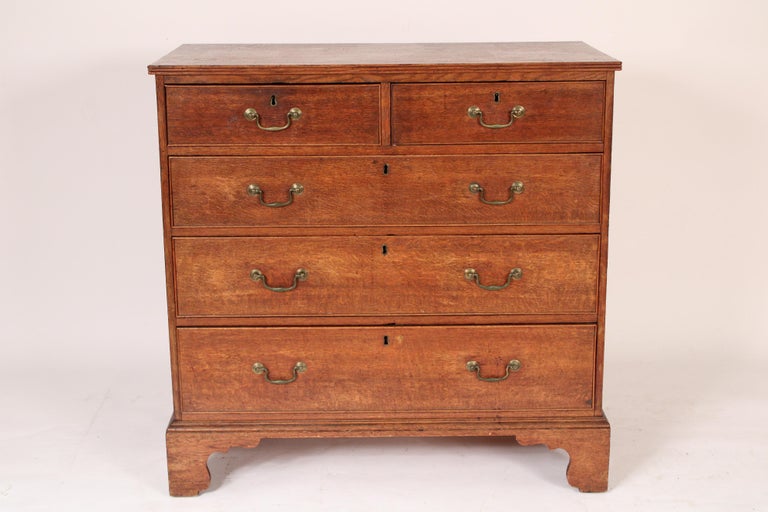 George III oak chest of drawers, circa 1800. With a slightly over hanging rectangular top with reeded molding on front and side edges, two top drawers, 3 graduated bottom drawers all with brass hardware, resting on bracket feet. Brass hardware is