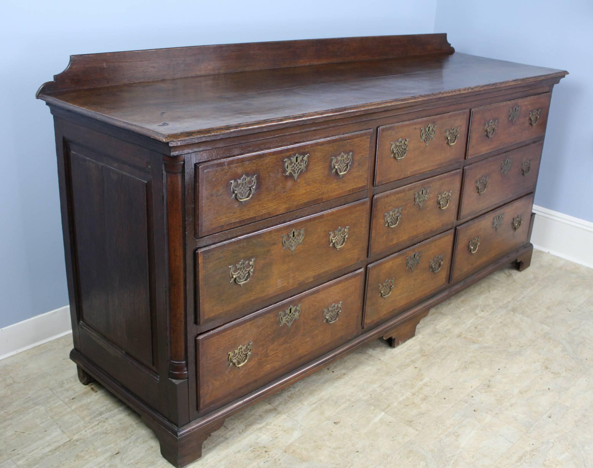 A large and dramatic nine-drawer 18th century enfilade or sideboard, very attractive with good patina and shine. The top is has a galleried back, and a good molding. Attractive brasses. At just under seven feet wide, this is a very practical piece.