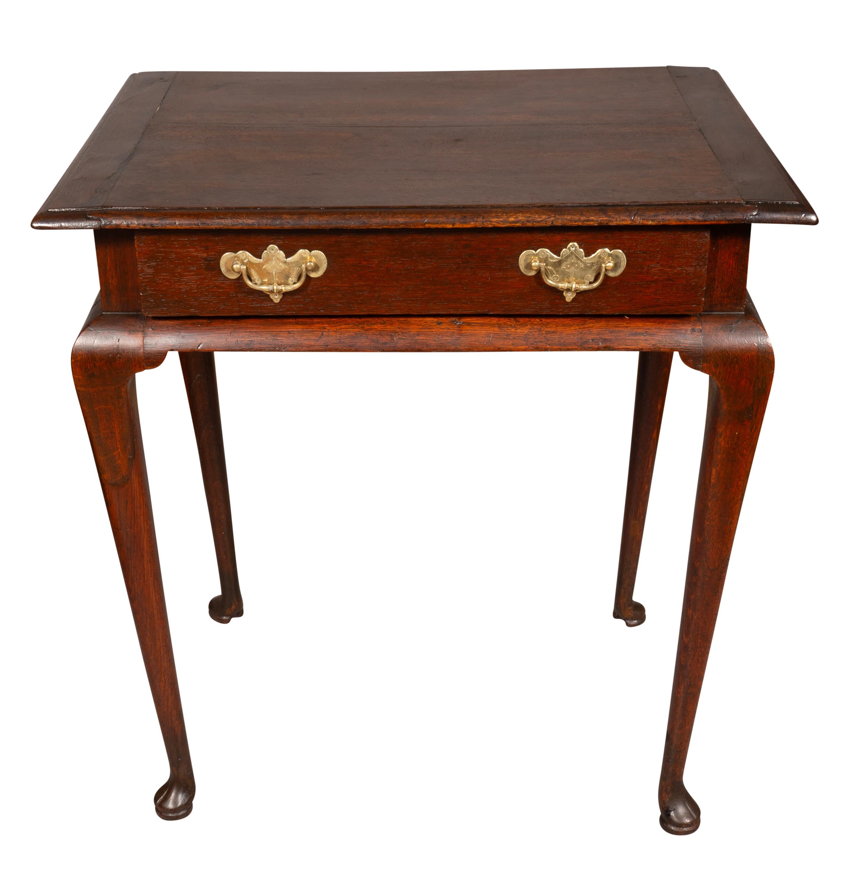 With a rectangular top over a drawer with a pair of brass handles. Raised on cabriole legs ending on pad feet.