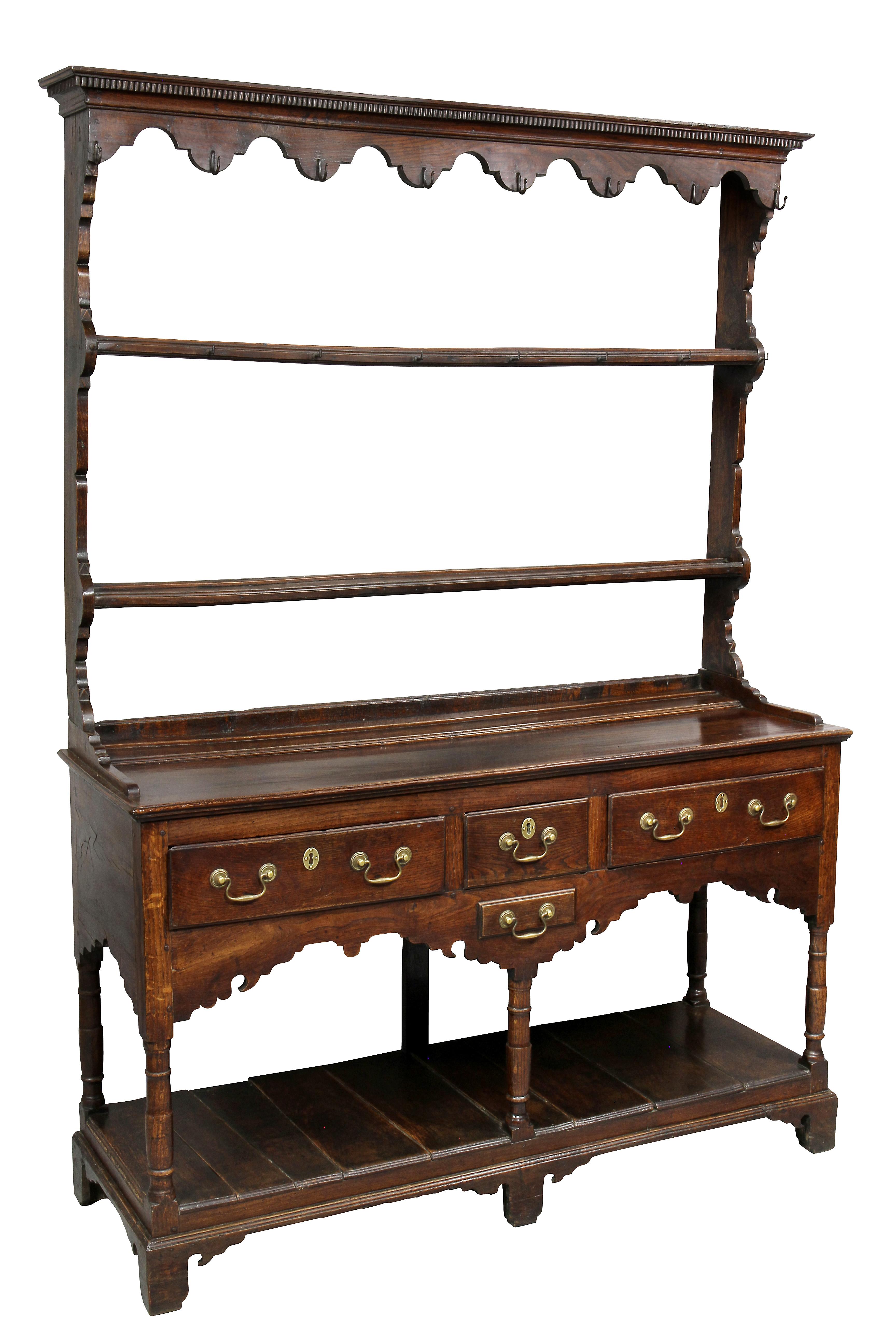 In two parts, with rectangular dentilled cornice and shaped frieze with iron cup hooks, two shelves, the base with a rectangular top over a small drawer flanked by two drawers, shaped apron containing a small drawer and lower pot shelf, bracket feet.