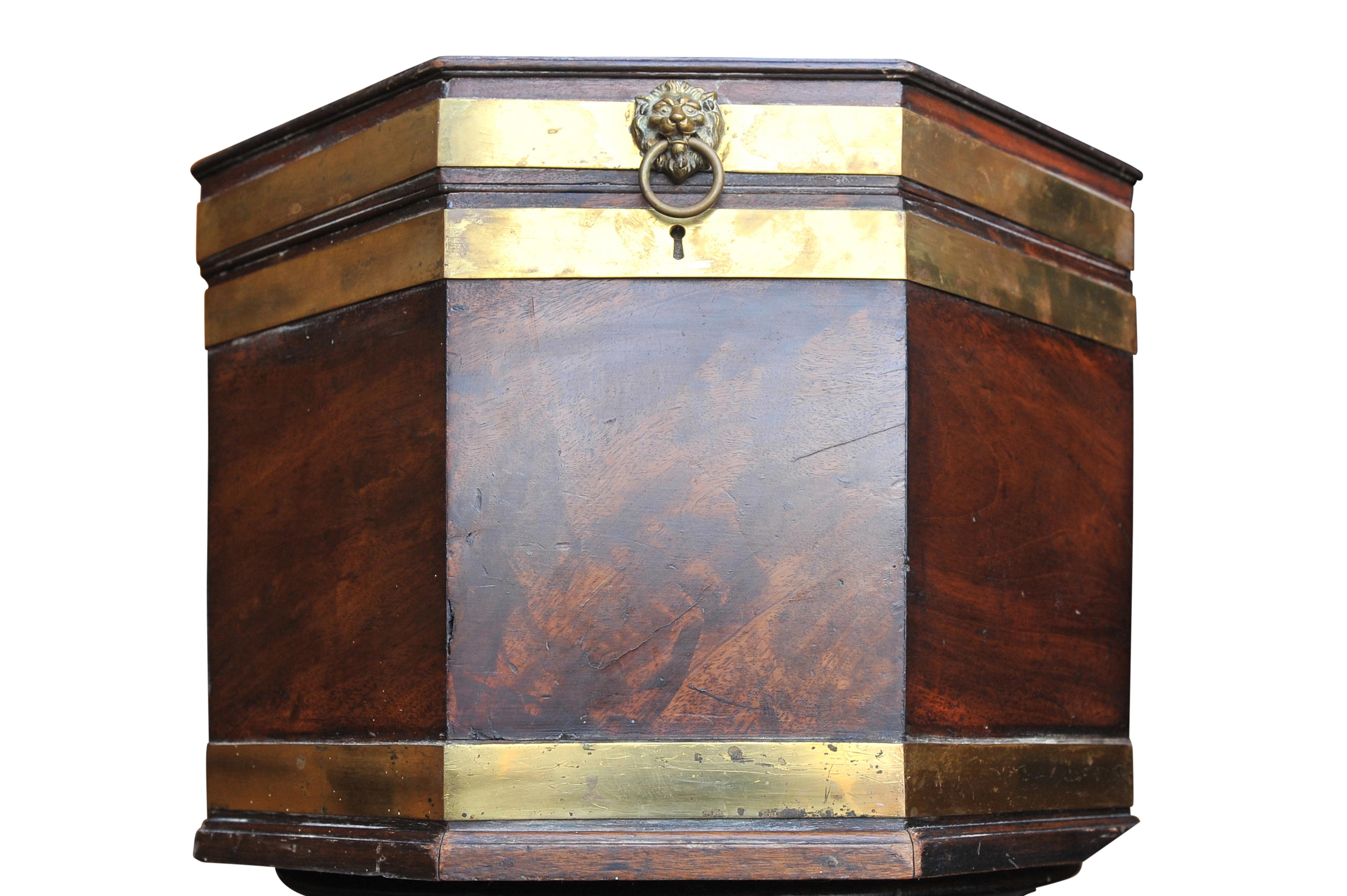 Cellarette de caoba y latón de forma octogonal de Jorge III, circa 1780, con asas laterales de latón y asa anular con máscara de león en la tapa con bisagras. 
Ideal para un bar seco o un centro de mesa.

Los recipientes de madera en forma de caja