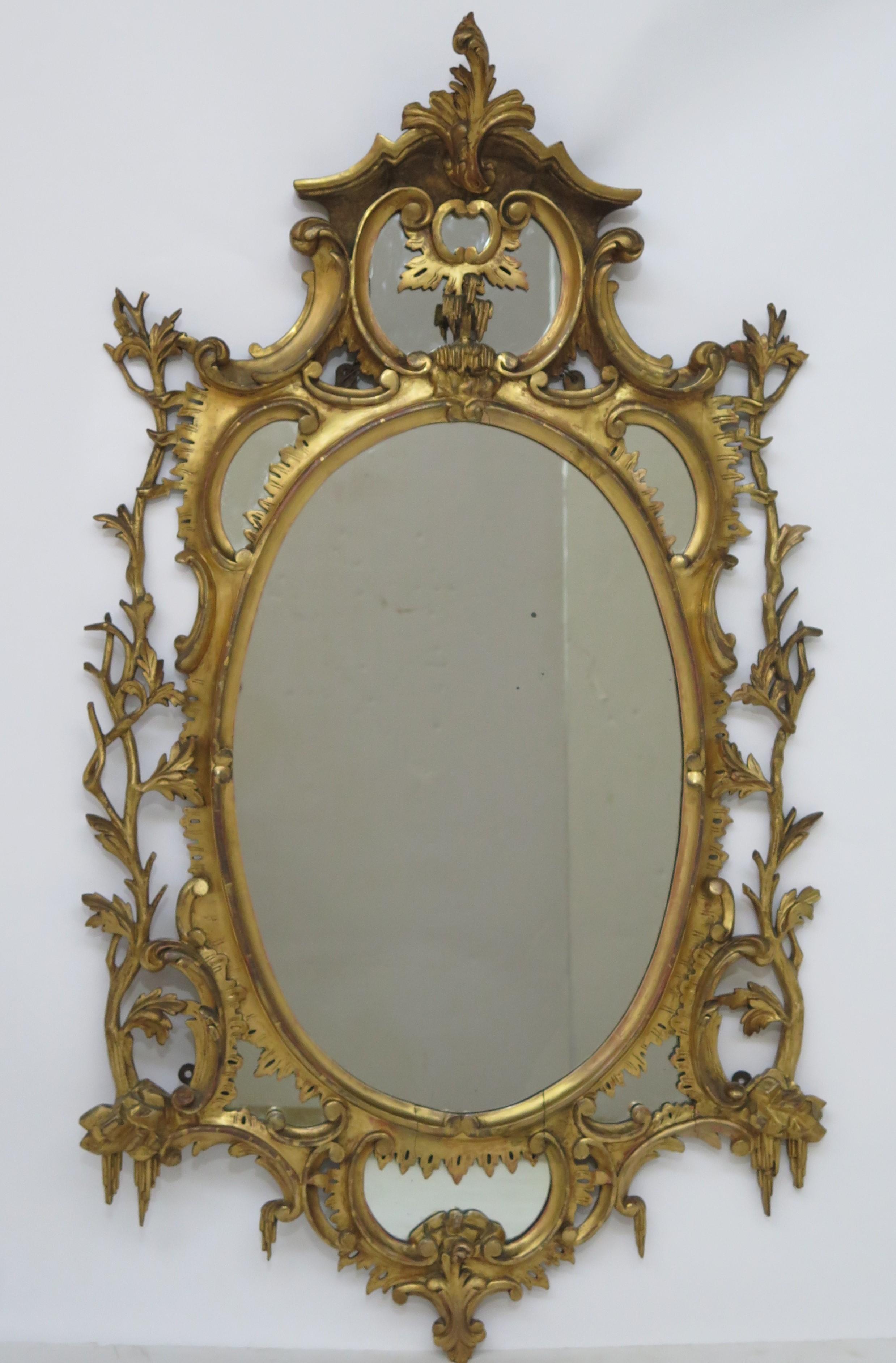 George III carved oval giltwood mirror in the Chippendale style, with elaborately carved molding, of branches and leaves on each side.