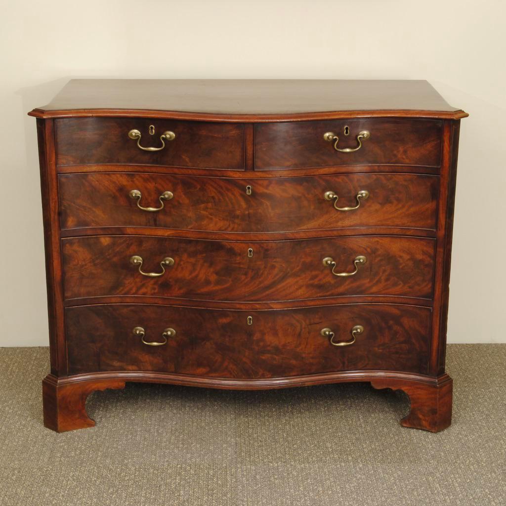 An 18th century flame mahogany serpentine shaped chest with graduated drawers two over three. Maintaining the original brass handles and super colour and patina, the canted corners with a fine box wood inlay. Fine quality with lovely oak linings to