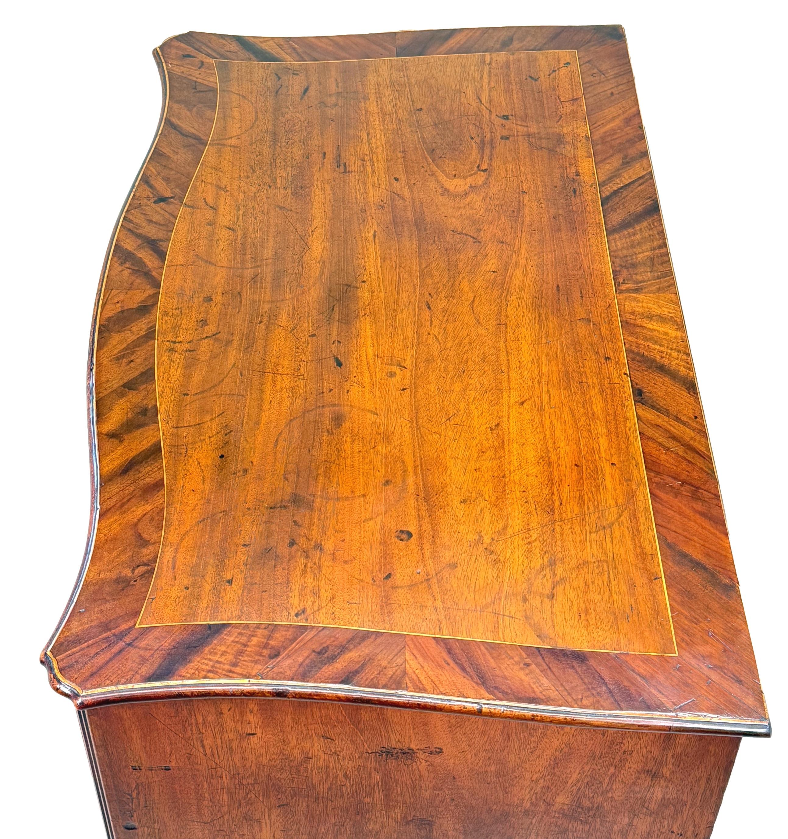 Cassettone a serpentina in mogano di ottima qualità del XVIII secolo, periodo Giorgio III, con piano sagomato e superbamente figurato, con un'attraente decorazione a fasce larghe, una slitta con spazzole a baia e quattro cassetti lunghi, con