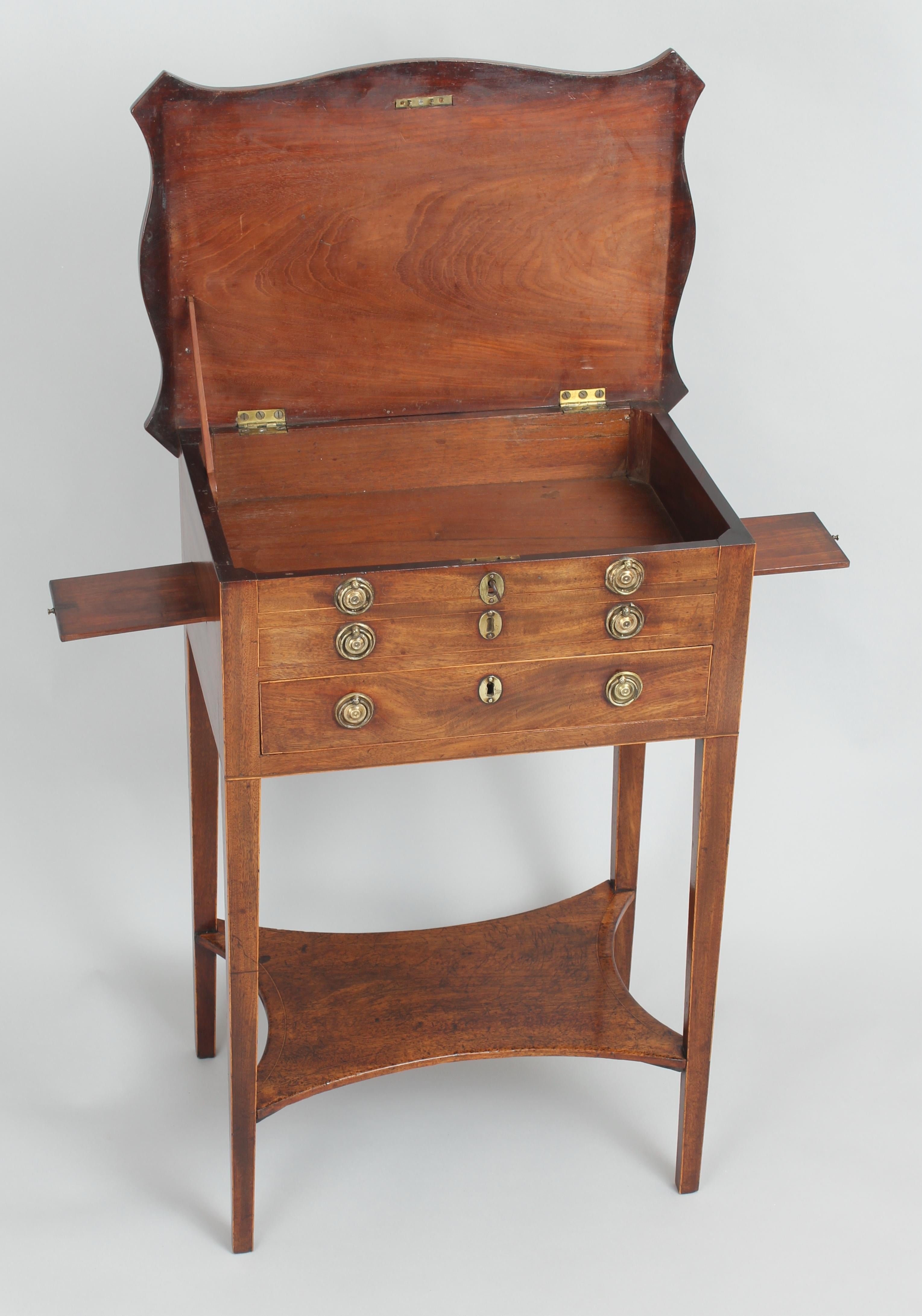 George III period mahogany worktable; the overhanging serpentine hinged top with a kingwood cross-banded border, enclosing a compartment behind two dummy-drawers, above a drawer with six adjustable dividers; the sides fitted with two small slides