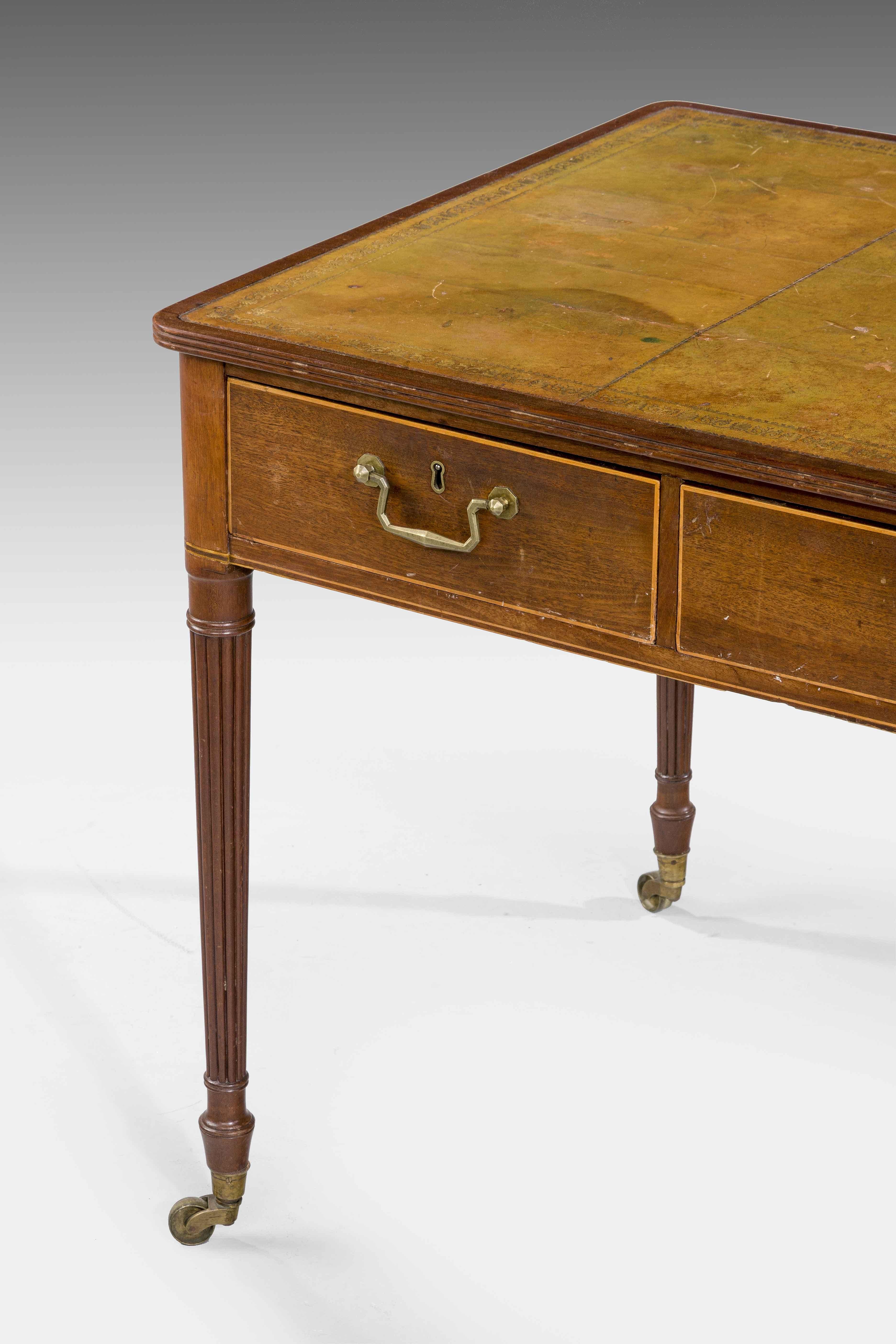 A good George III period mahogany writing table, the front with three oak lined drawers, the reverse with dummy drawers. Finely turned and fluted supports, inset leather top which is old and probably not original and now somewhat tired. Good square