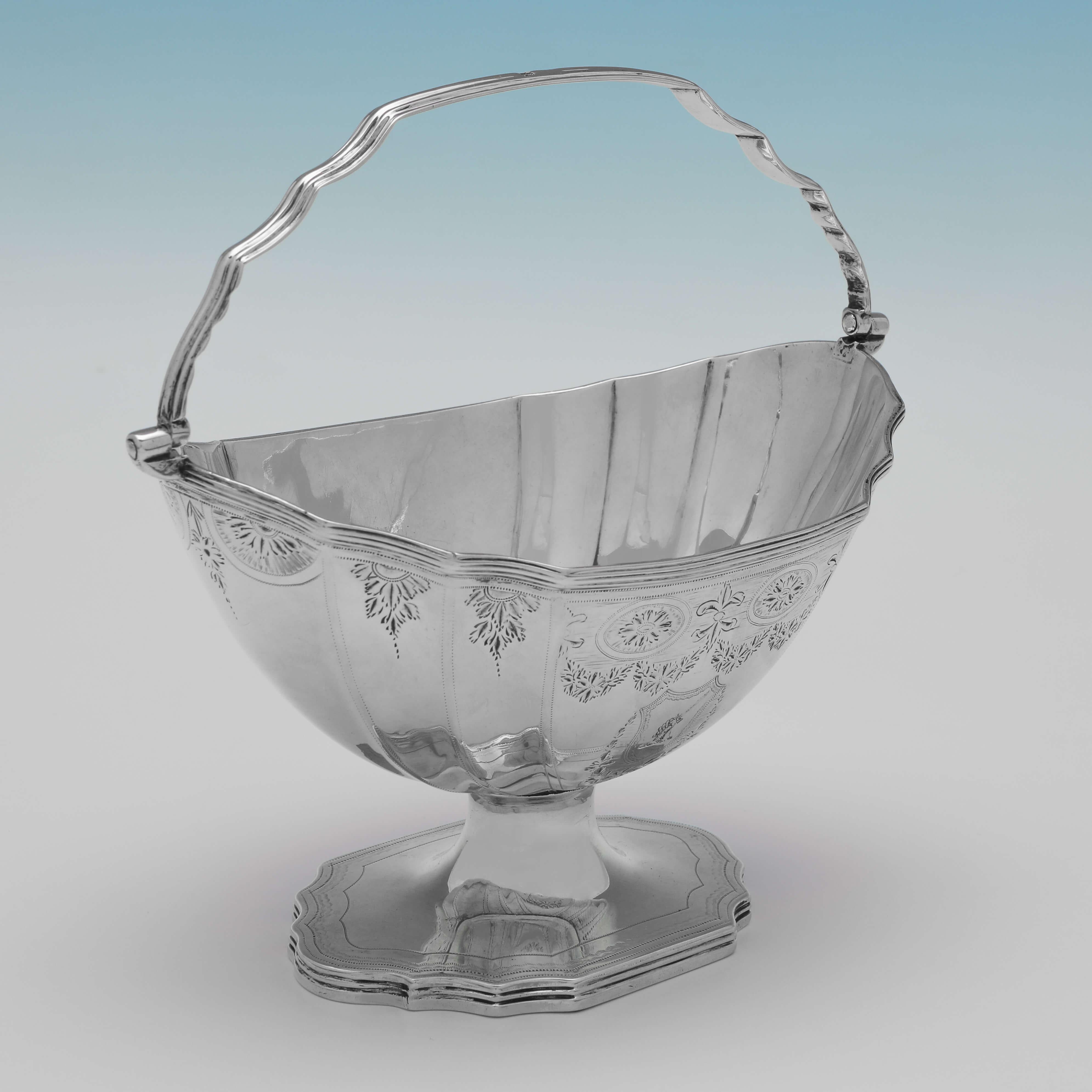 Hallmarked in London in 1795 by Solomon Hougham, this attractive, George III period, Antique Sterling Silver Sugar Basket, is in the Neoclassical taste, with engraved decoration to the body and foot, a swing handle, and an engraved crest to one