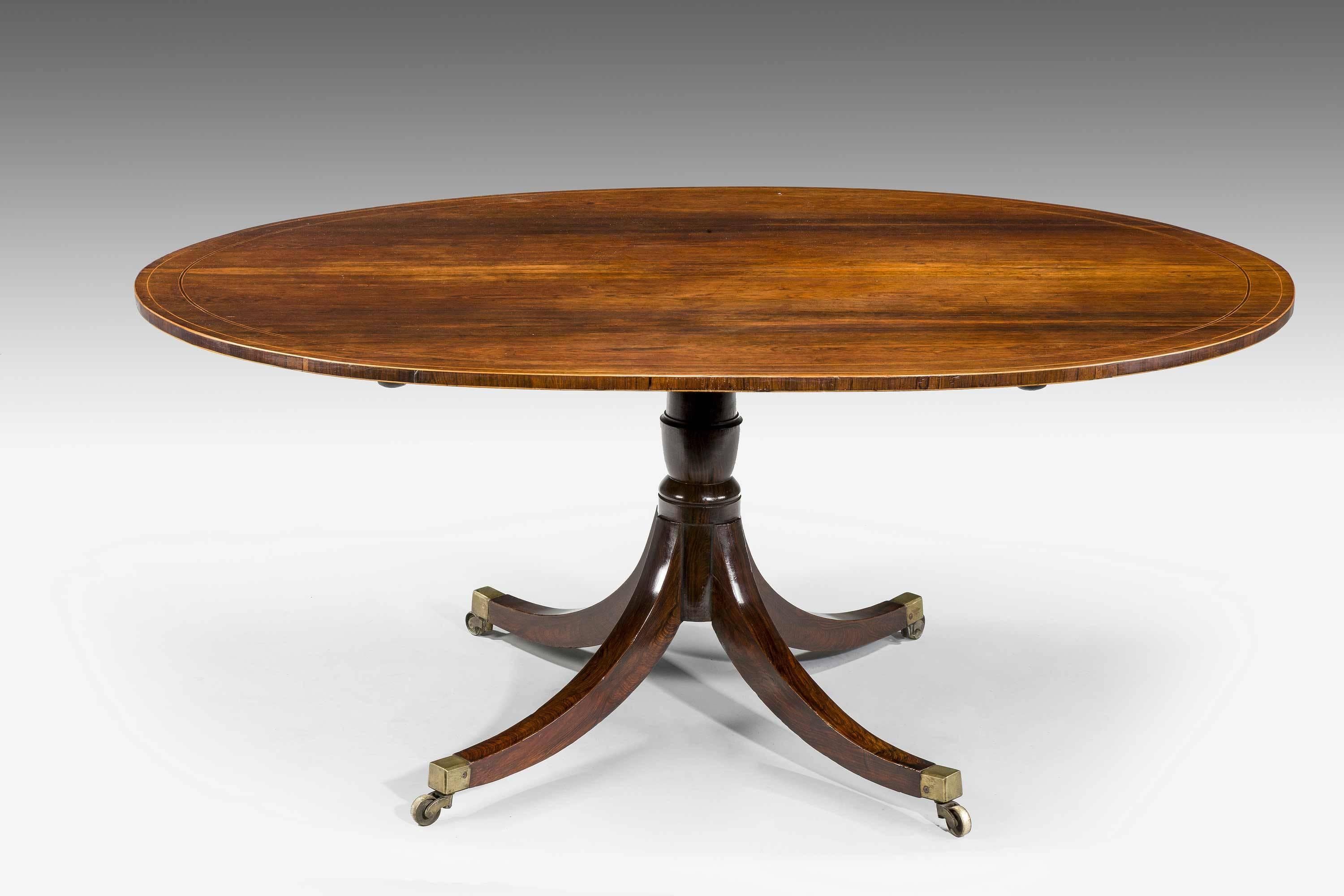 George III period mahogany oval dining table of very good colour and patina, the top with fine line banding the support over four square section swept legs. Original shoes and castors.