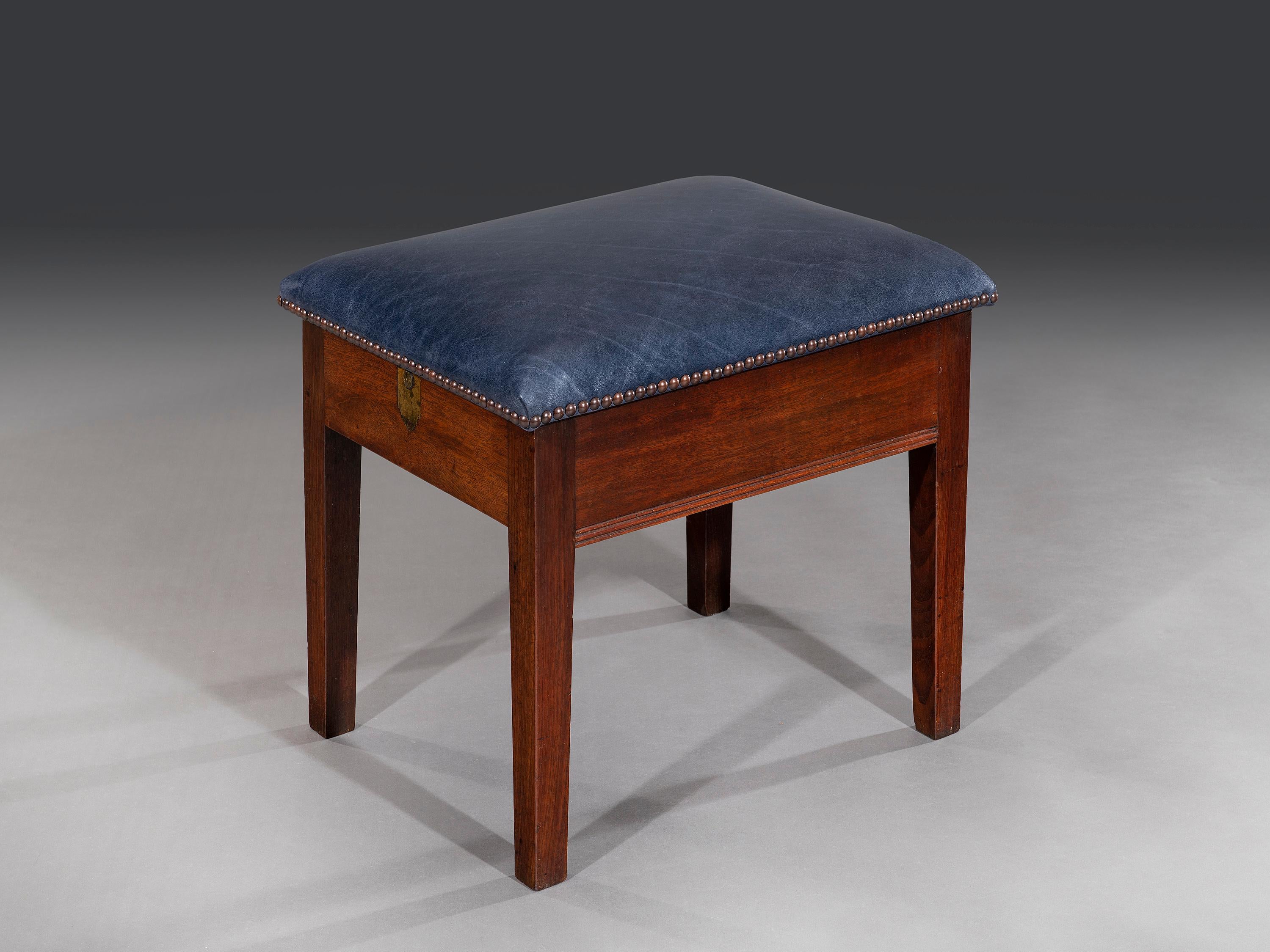 The unusual set of 18th century metamorphic library steps is concealed in the form of a library stool. The recently upholstered hinged seat has been re-covered in blue leather hide and opens when the brass button is pressed to release the catch. The