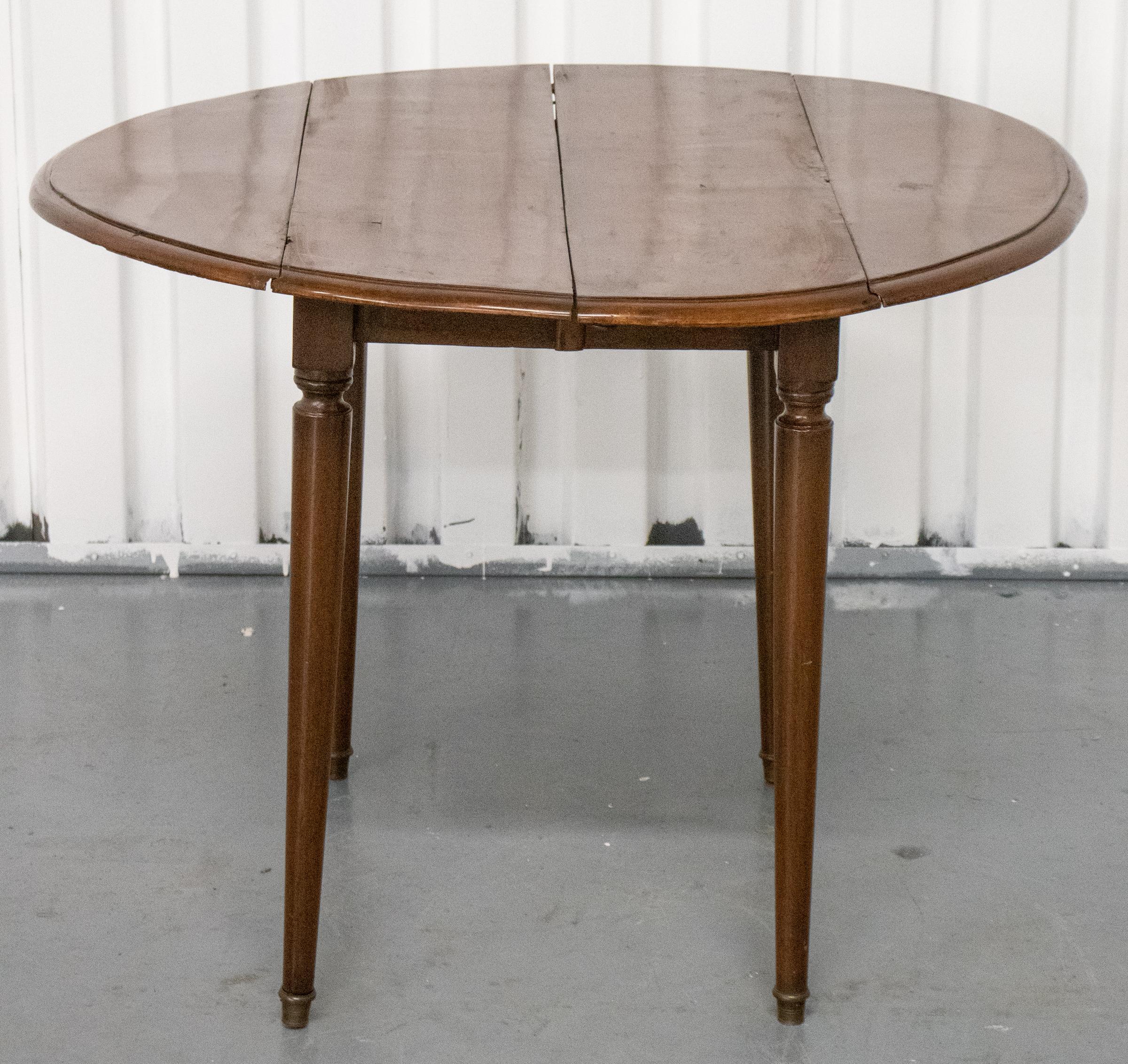 George III Provincial mahogany dining table, circa 1800, the top with two D-form drop flaps above the tapered column legs raised on brass caps, with three leaves. Measures: 28” H x 38” W x 20” D, leaves 13