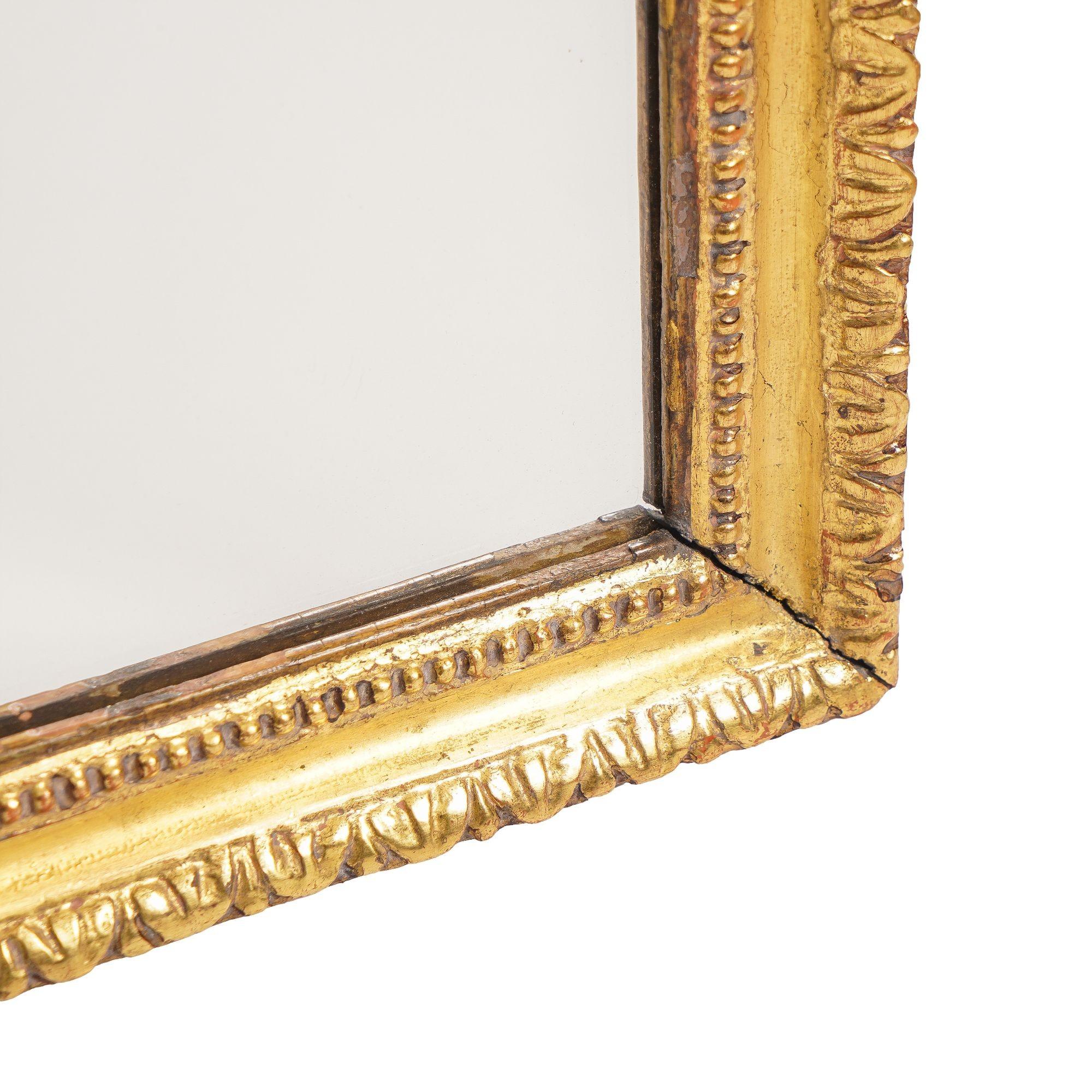 George III rectangular overmantle mirror of gilt gesso on carved pine. The molding is defined by its gadroon carved back band & lamb’s tongue carved with radius cut upper corners. The mirror glass has been replaced.
England, circa 1770.
